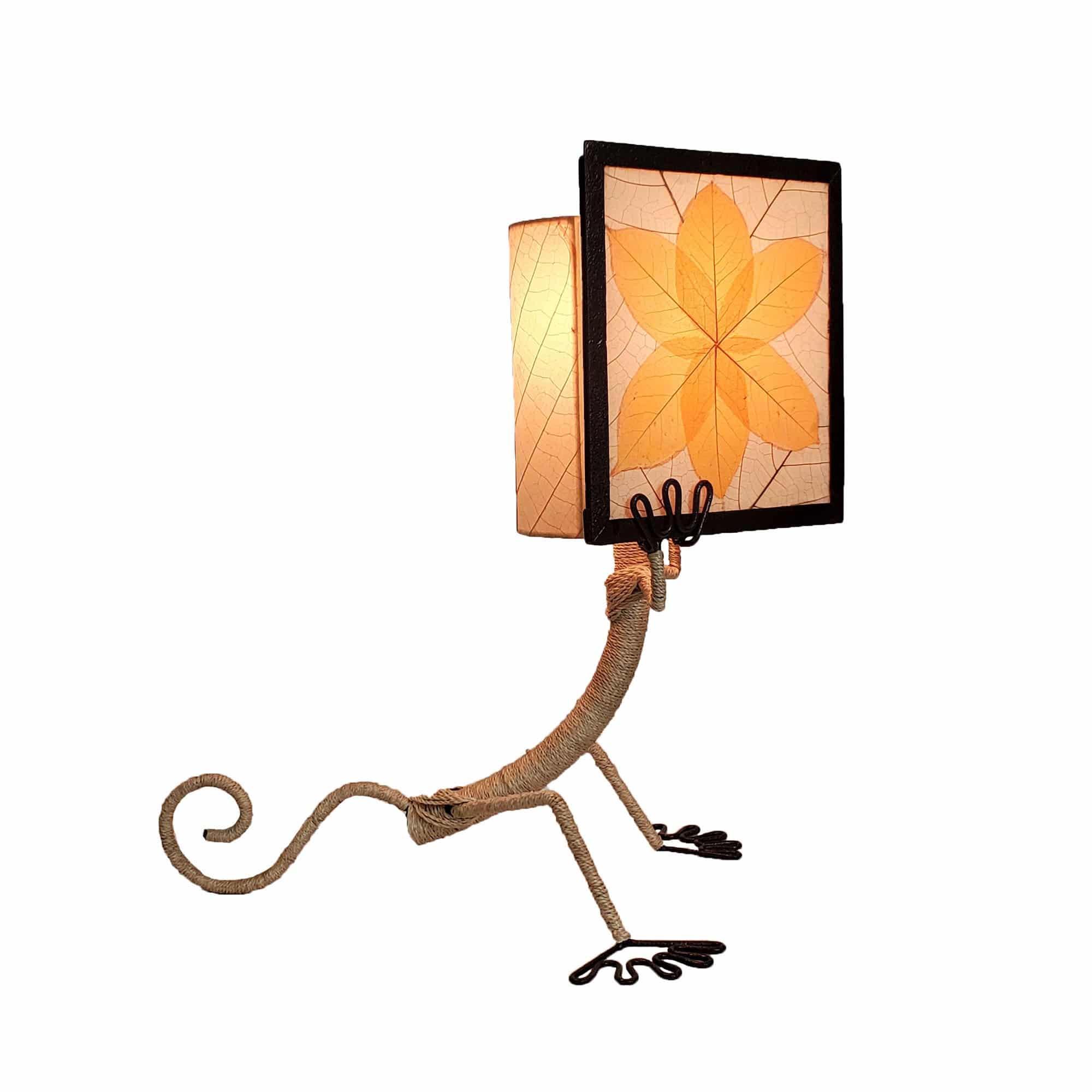 Crafted by the artisans of Eangee Home Design, the Enlightened Gecko Table Lamp in orange against a clean backdrop, featuring fossilized cocoa leaf shade, guyabano leaf shade, abaca rope accents, wrought iron frame, handcrafted.