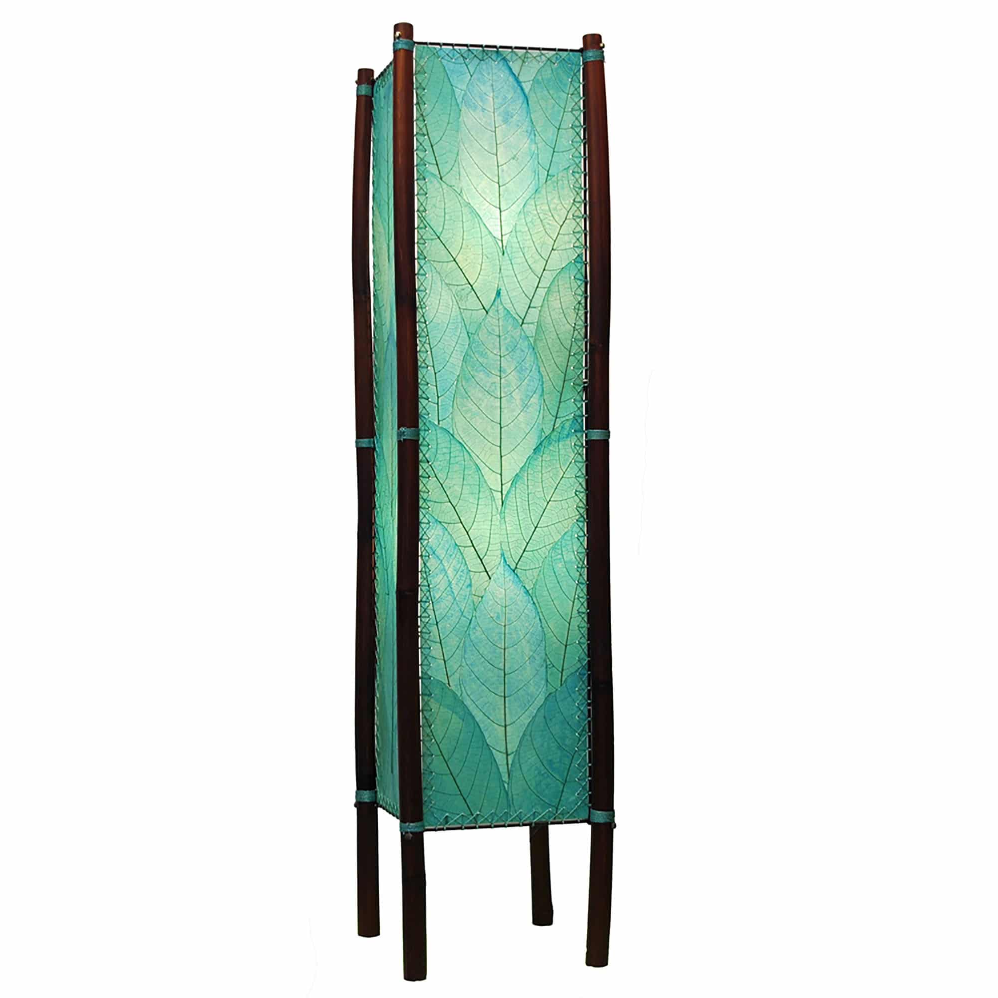In a minimalist loft with natural textures, crafted by the artisans of Eangee Home Design, the Fortune Large Floor Lamp in sea blue stands gracefully, featuring fossilized cocoa leaf shade, abaca rope accents, rattan leg supports, wrought iron frame, handcrafted, adding warmth and character to the space.