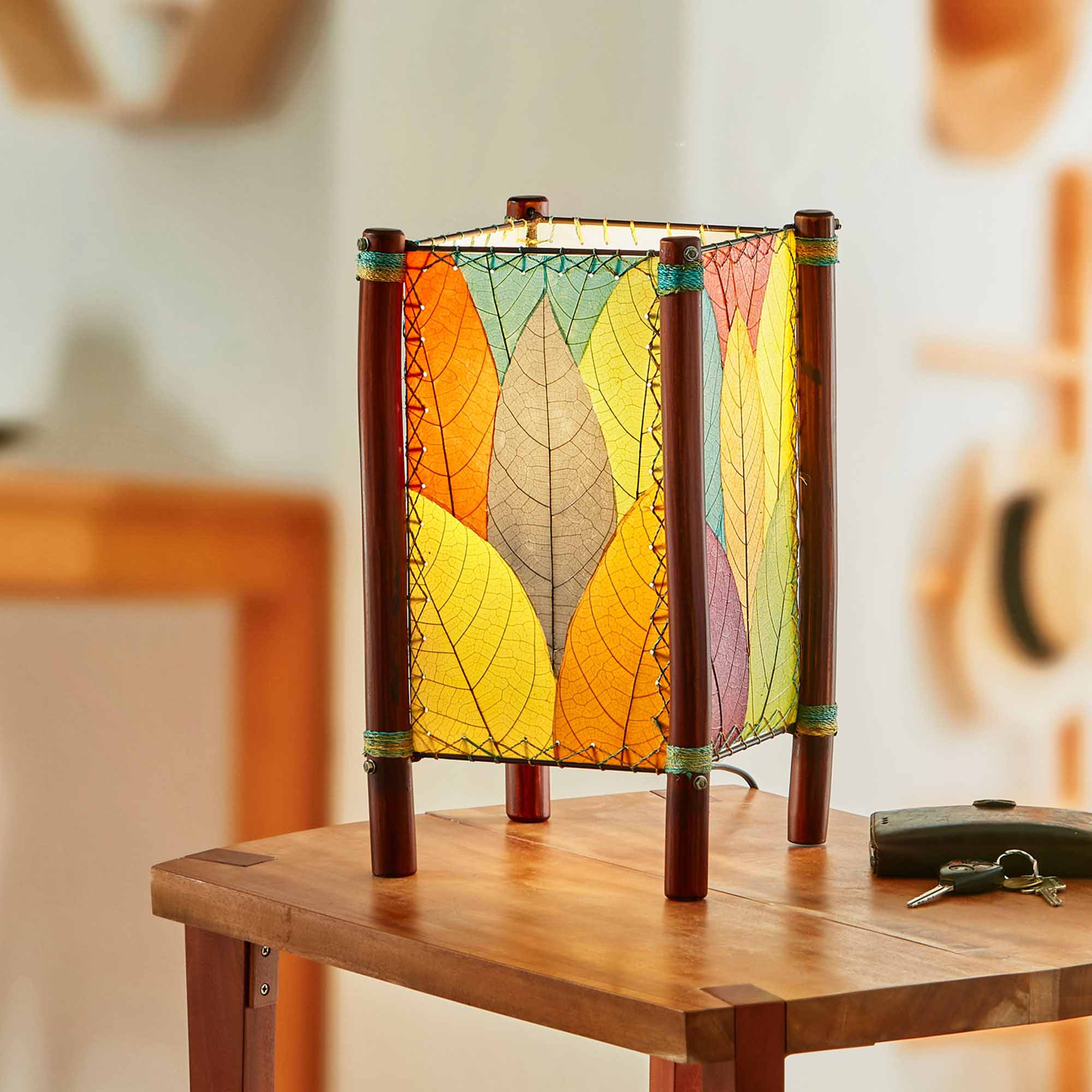 In a modern interior with earth tones, crafted by the artisans of Eangee Home Design, the Fortune Table Lamp in multi color stands gracefully, featuring fossilized cocoa leaf shade, abaca rope accents, rattan leg supports, adding warmth and character to the space.