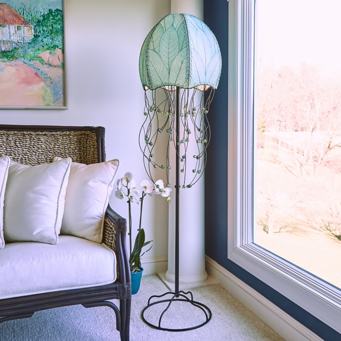 In a quiet bedside corner, crafted by the artisans of Eangee Home Design, the Jellyfish Large Floor Lamp in sea blue stands gracefully, featuring fossilized cocoa leaf shade, wrought iron frame, eco friendly, adding warmth and character to the space.