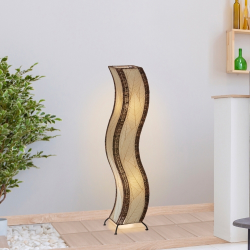 In a modern interior with earth tones, crafted by the artisans of Eangee Home Design, the Wave Large Floor Lamp in natural stands gracefully, featuring fossilized cocoa leaf shade, abaca rope accents, handcrafted, adding warmth and character to the space.
