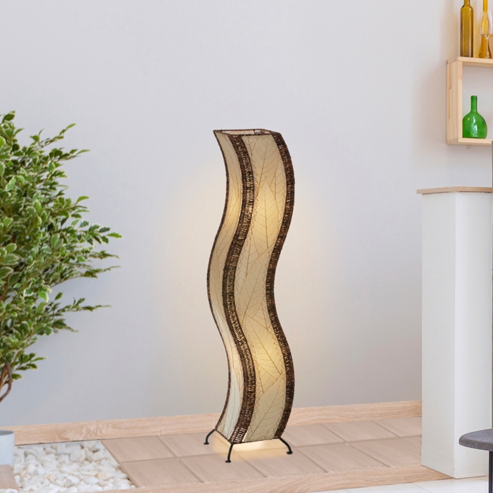 In a modern interior with earth tones, crafted by the artisans of Eangee Home Design, the Wave Large Floor Lamp in natural stands gracefully, featuring fossilized cocoa leaf shade, abaca rope accents, handcrafted, adding warmth and character to the space.