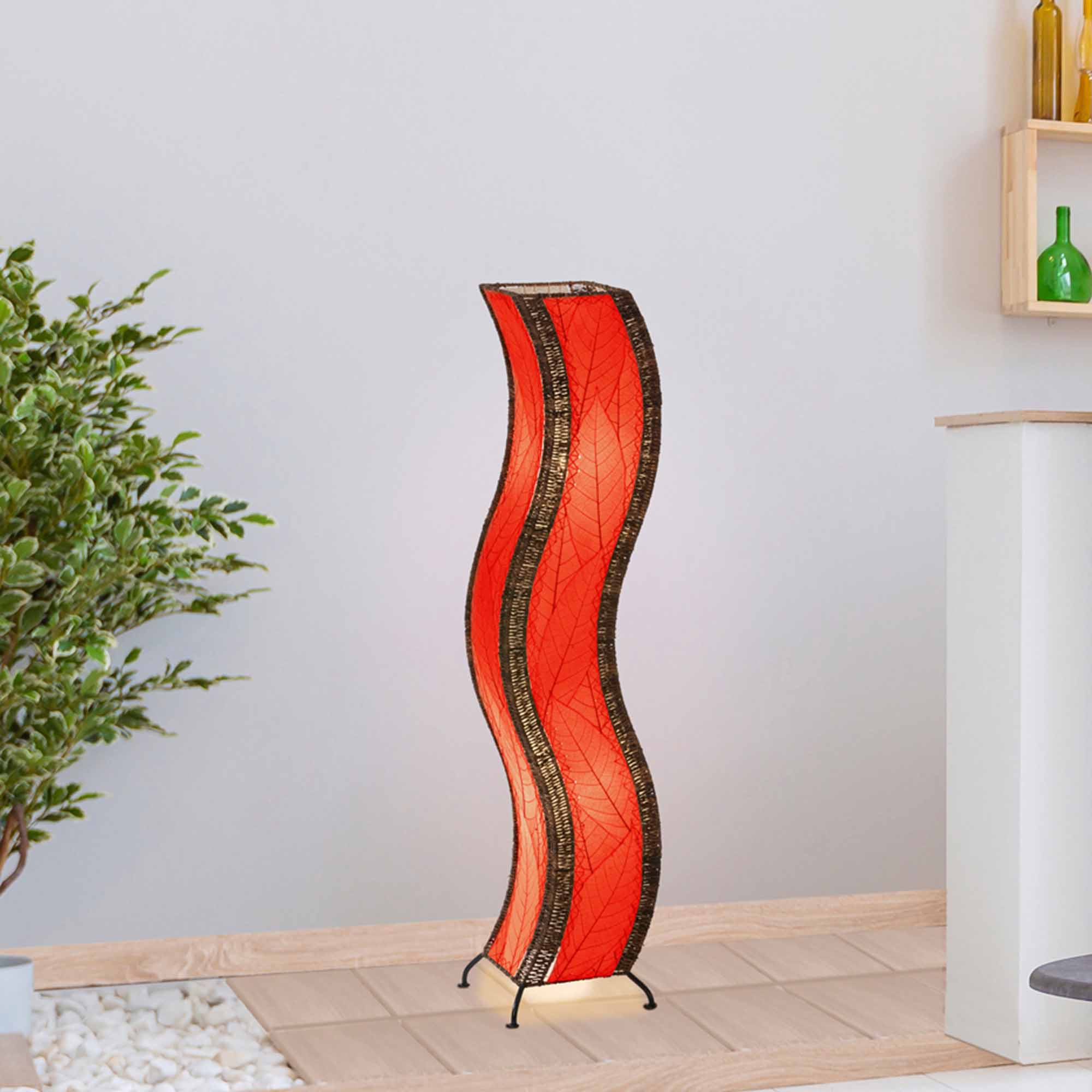 In a quiet bedside corner, crafted by the artisans of Eangee Home Design, the Wave Large Floor Lamp in red stands gracefully, featuring fossilized cocoa leaf shade, abaca rope accents, handcrafted, adding warmth and character to the space.