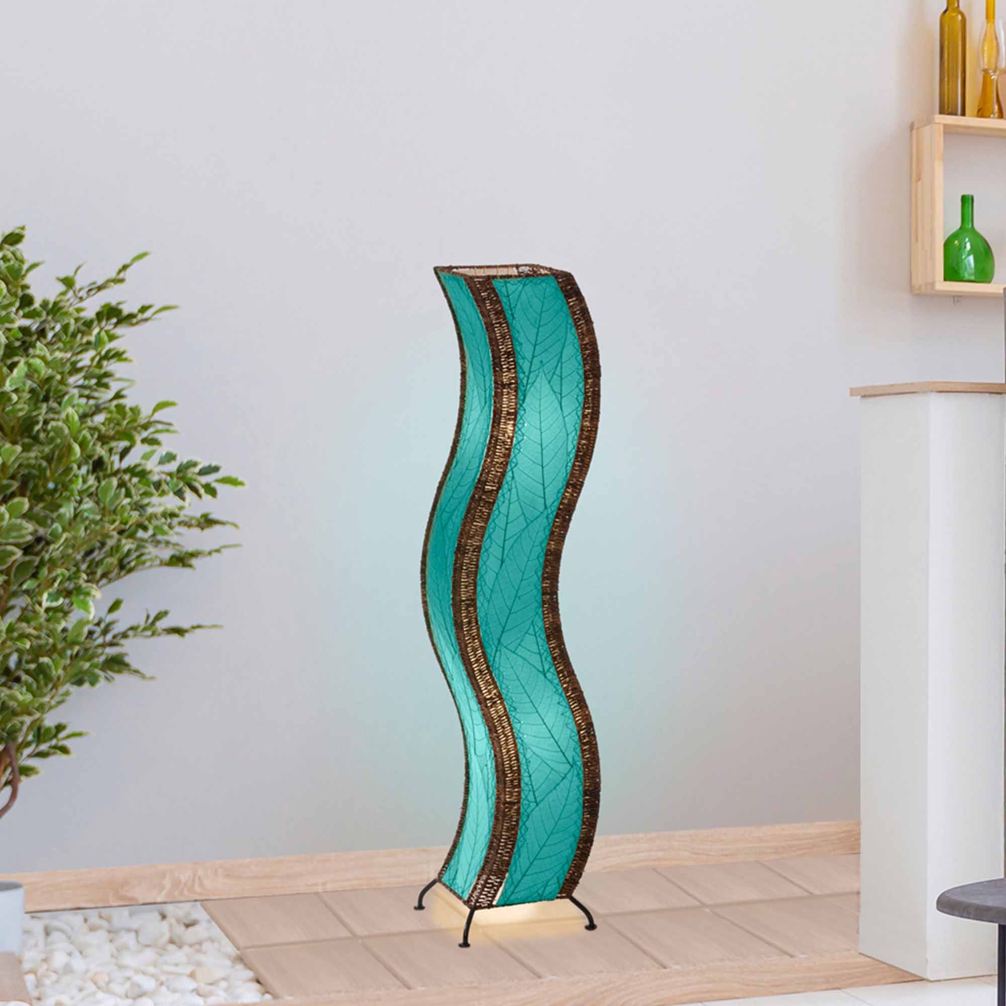 In a quiet bedside corner, crafted by the artisans of Eangee Home Design, the Wave Large Floor Lamp in sea blue stands gracefully, featuring fossilized cocoa leaf shade, abaca rope accents, handcrafted, adding warmth and character to the space.