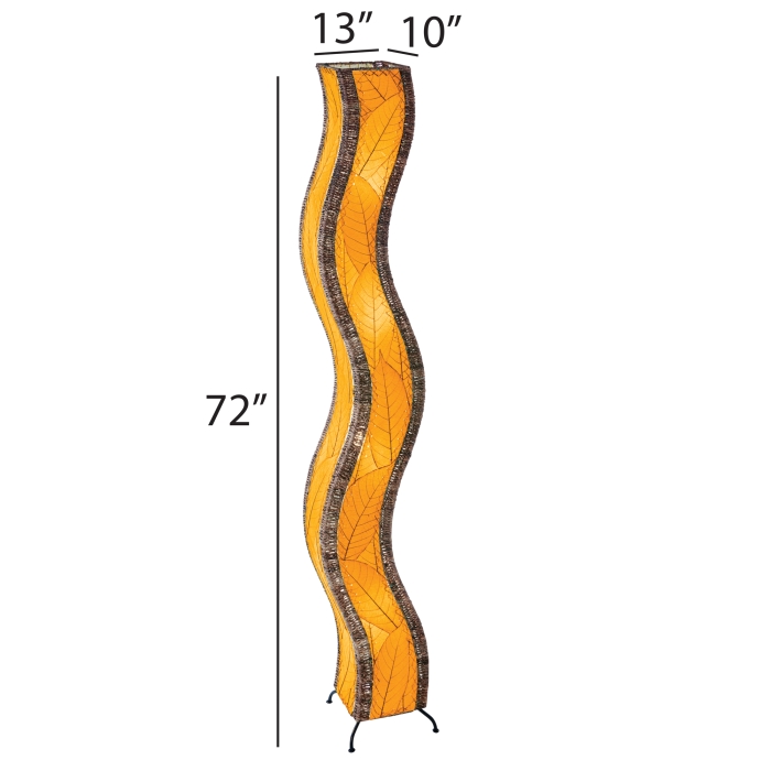 The Eangee Home Design Wave Giant Floor Lamp Orange (Item #457 xl o), featuring brown edges, stands on a light wood floor near a green plant, with shelves of colorful glass bottles and a gray counter in the background.