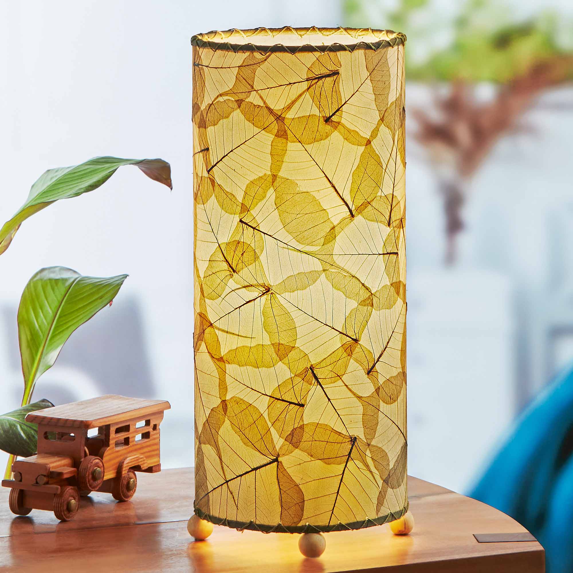 In a modern interior with earth tones, crafted by the artisans of Eangee Home Design, the Banyan Table Lamp in green stands gracefully, featuring wrought iron frame, eco friendly, adding warmth and character to the space.