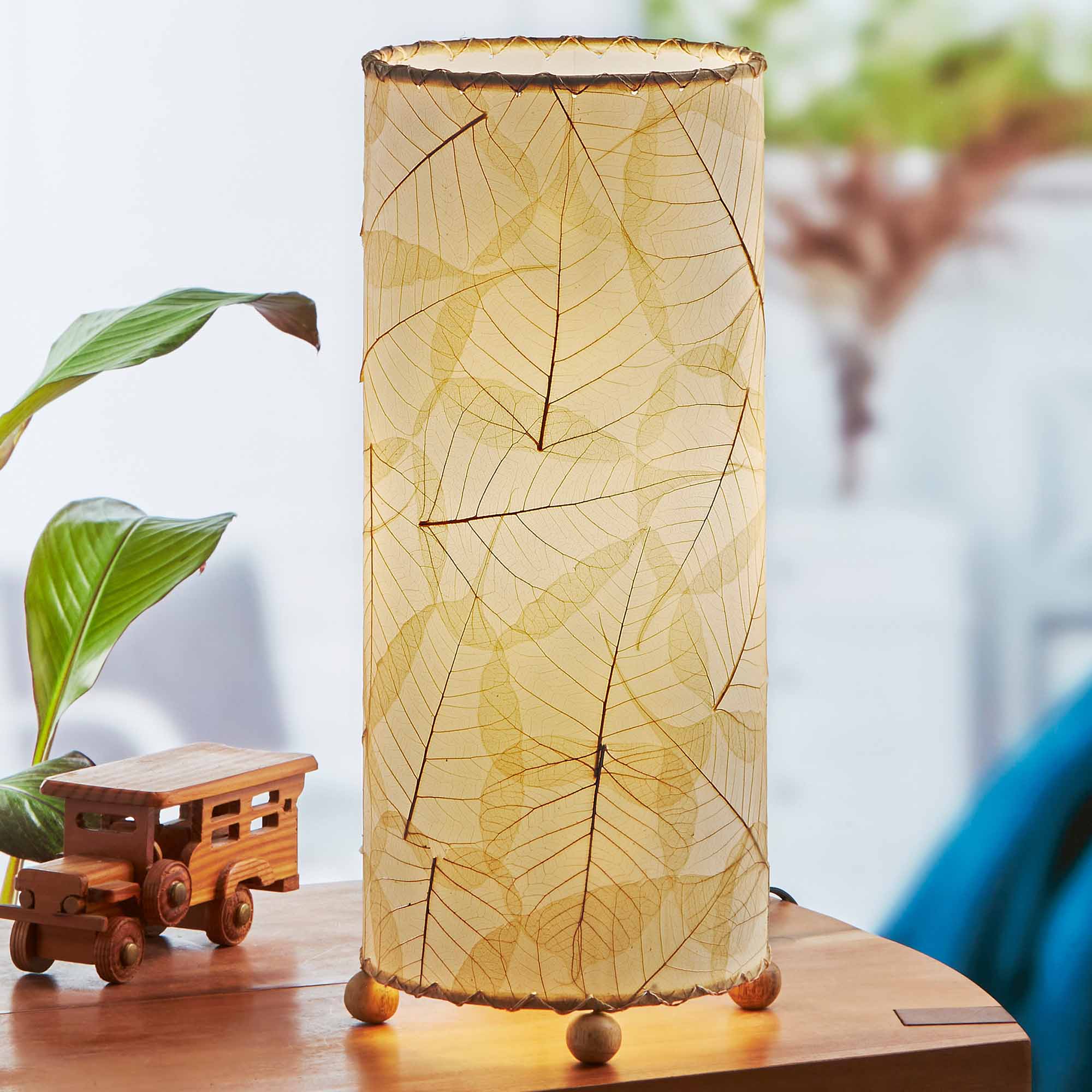 In a quiet bedside corner, crafted by the artisans of Eangee Home Design, the Banyan Table Lamp in natural stands gracefully, featuring wrought iron frame, eco friendly, adding warmth and character to the space.