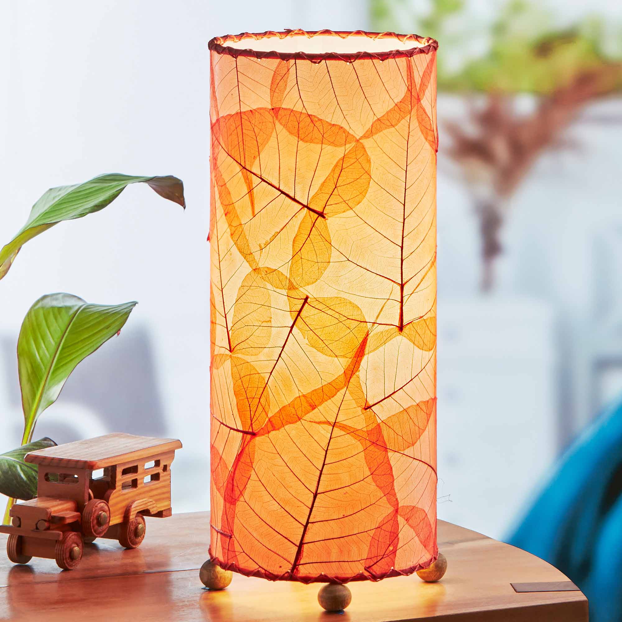 In a modern interior with earth tones, crafted by the artisans of Eangee Home Design, the Banyan Table Lamp in red stands gracefully, featuring wrought iron frame, eco friendly, adding warmth and character to the space.