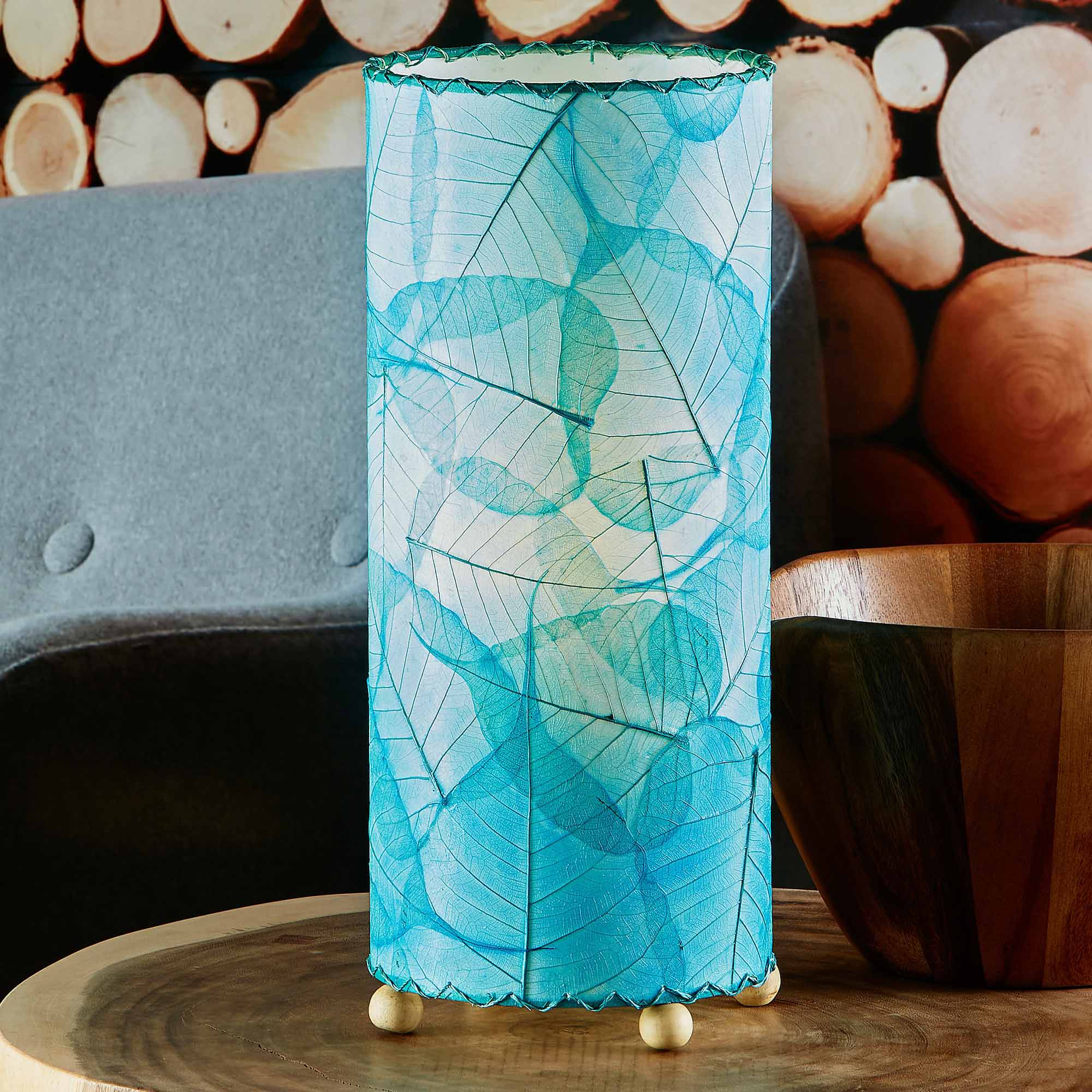 In a softly lit reading nook, crafted by the artisans of Eangee Home Design, the Banyan Table Lamp in sea blue stands gracefully, featuring wrought iron frame, eco friendly, adding warmth and character to the space.