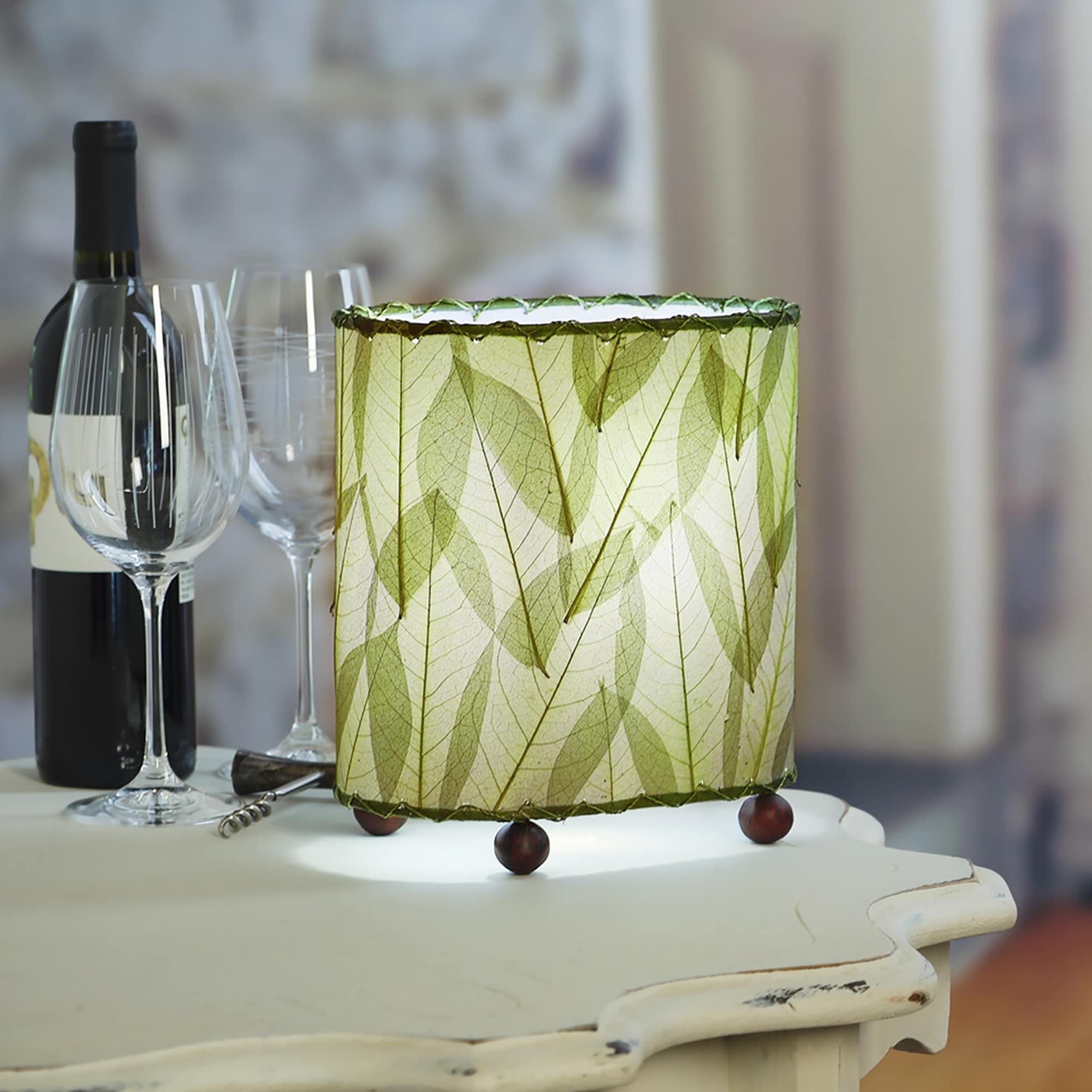 Crafted by the artisans of Eangee Home Design, the Mini Guyabano Table Lamp in green against a clean backdrop, featuring fossilized cocoa leaf shade, guyabano leaf shade, wrought iron frame.