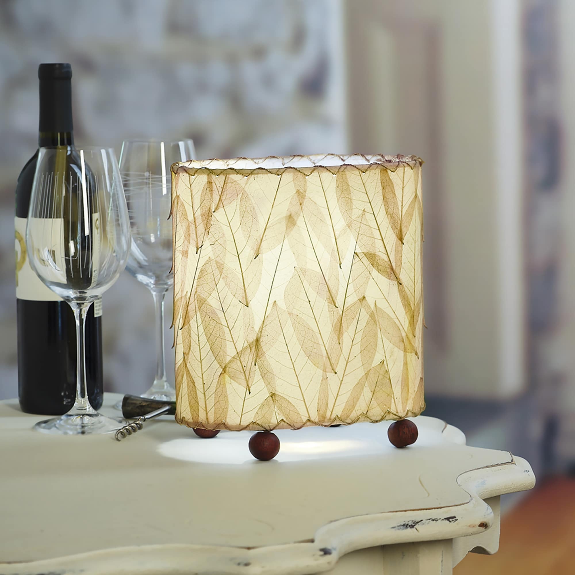 Crafted by the artisans of Eangee Home Design, the Mini Guyabano Table Lamp in natural against a clean backdrop, featuring fossilized cocoa leaf shade, guyabano leaf shade, wrought iron frame.