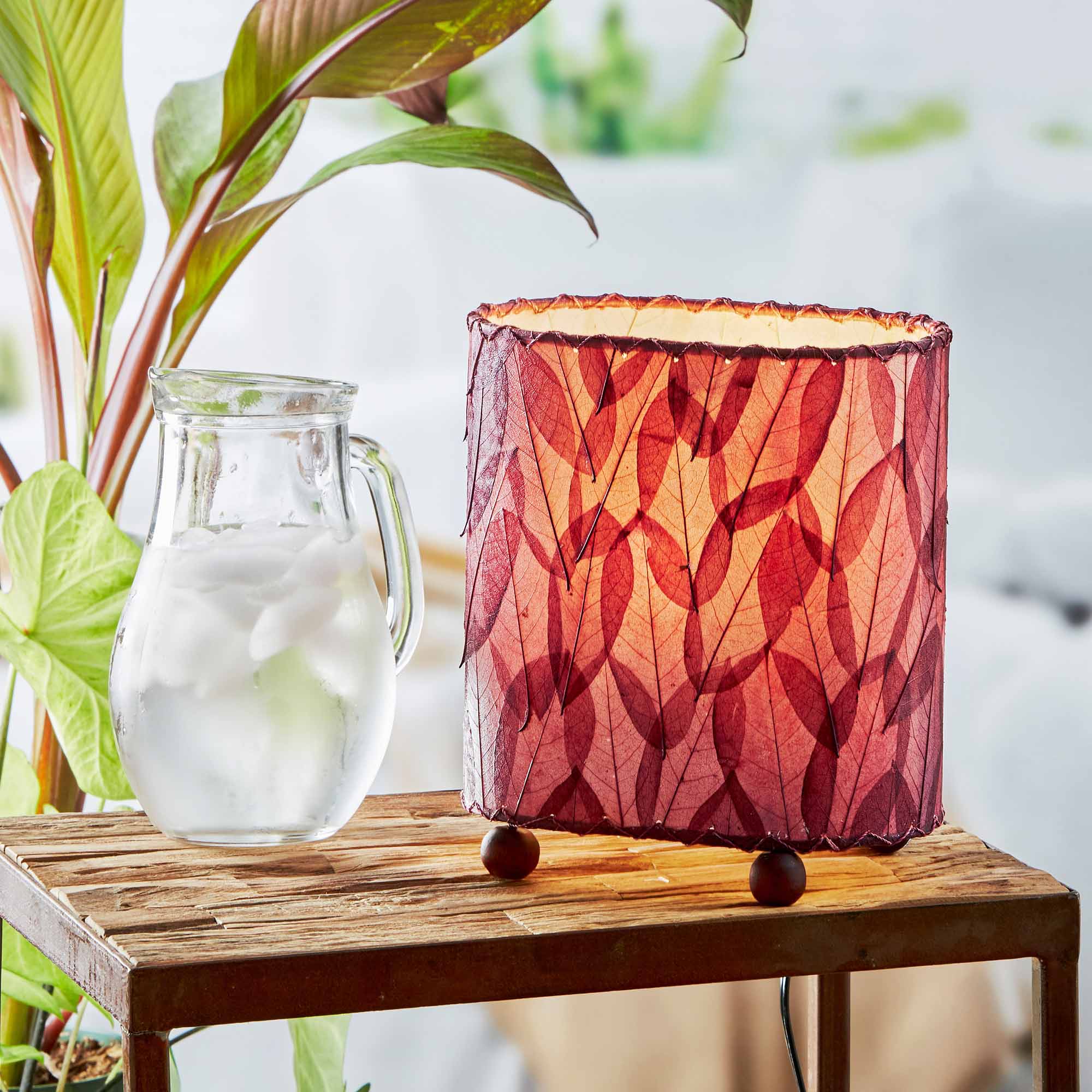 In a quiet bedside corner, crafted by the artisans of Eangee Home Design, the Mini Guyabano Table Lamp in purple stands gracefully, featuring fossilized cocoa leaf shade, guyabano leaf shade, wrought iron frame, adding warmth and character to the space.