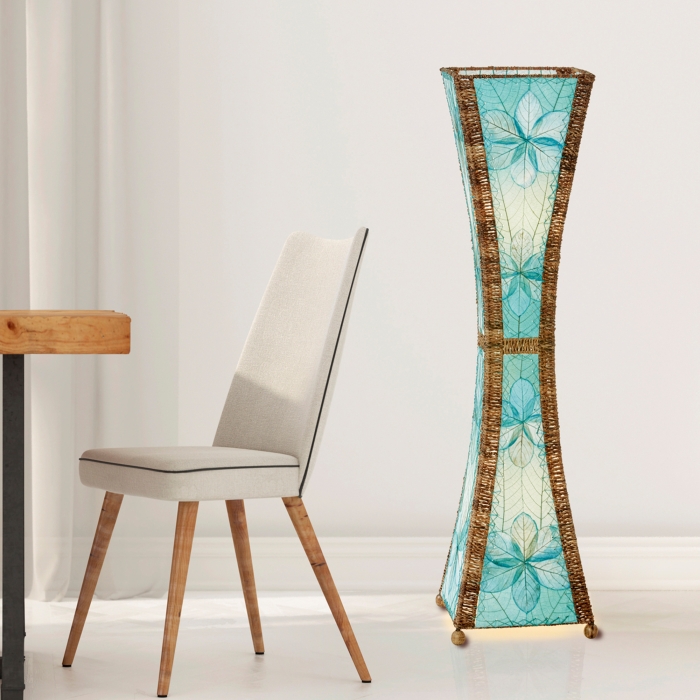 In a sun drenched entryway, crafted by the artisans of Eangee Home Design, the Hourglass Large Floor Lamp in sea blue stands gracefully, featuring jackfruit leaf panels, abaca rope accents, fair trade, eco friendly, sustainably sourced, adding warmth and character to the space.