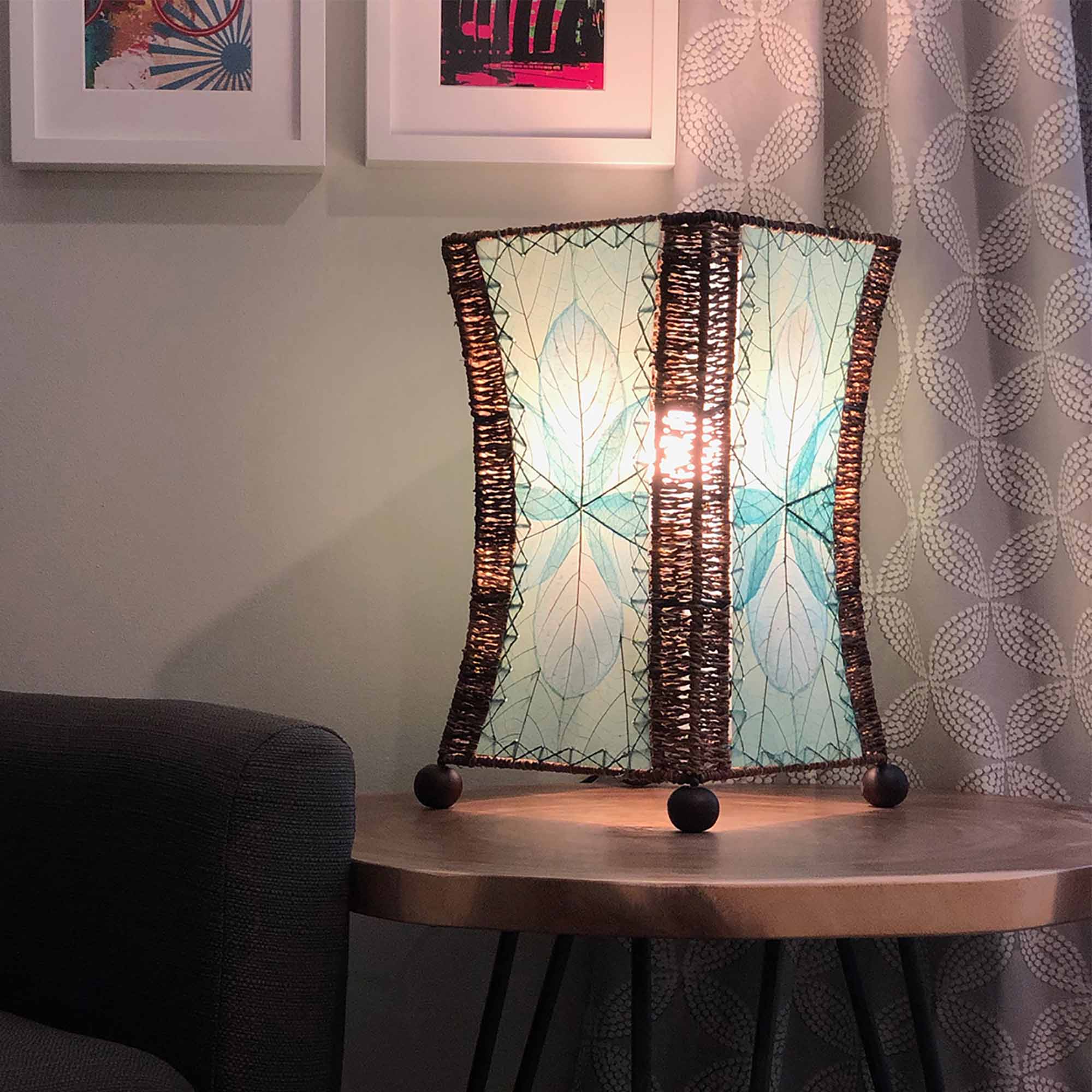 In a coastal inspired living room, crafted by the artisans of Eangee Home Design, the Hourglass Table Lamp in sea blue stands gracefully, featuring jackfruit leaf panels, abaca rope accents, wrought iron frame, eco friendly, adding warmth and character to the space.