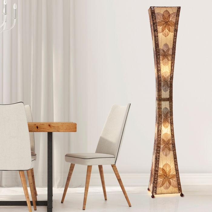 In a sun drenched entryway, crafted by the artisans of Eangee Home Design, the Hourglass Giant Floor Lamp in natural stands gracefully, featuring jackfruit leaf panels, abaca rope accents, wrought iron frame, eco friendly, handcrafted, adding warmth and character to the space.