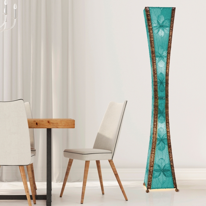 In a softly lit reading nook, crafted by the artisans of Eangee Home Design, the Hourglass Giant Floor Lamp in sea blue stands gracefully, featuring jackfruit leaf panels, abaca rope accents, wrought iron frame, eco friendly, handcrafted, adding warmth and character to the space.