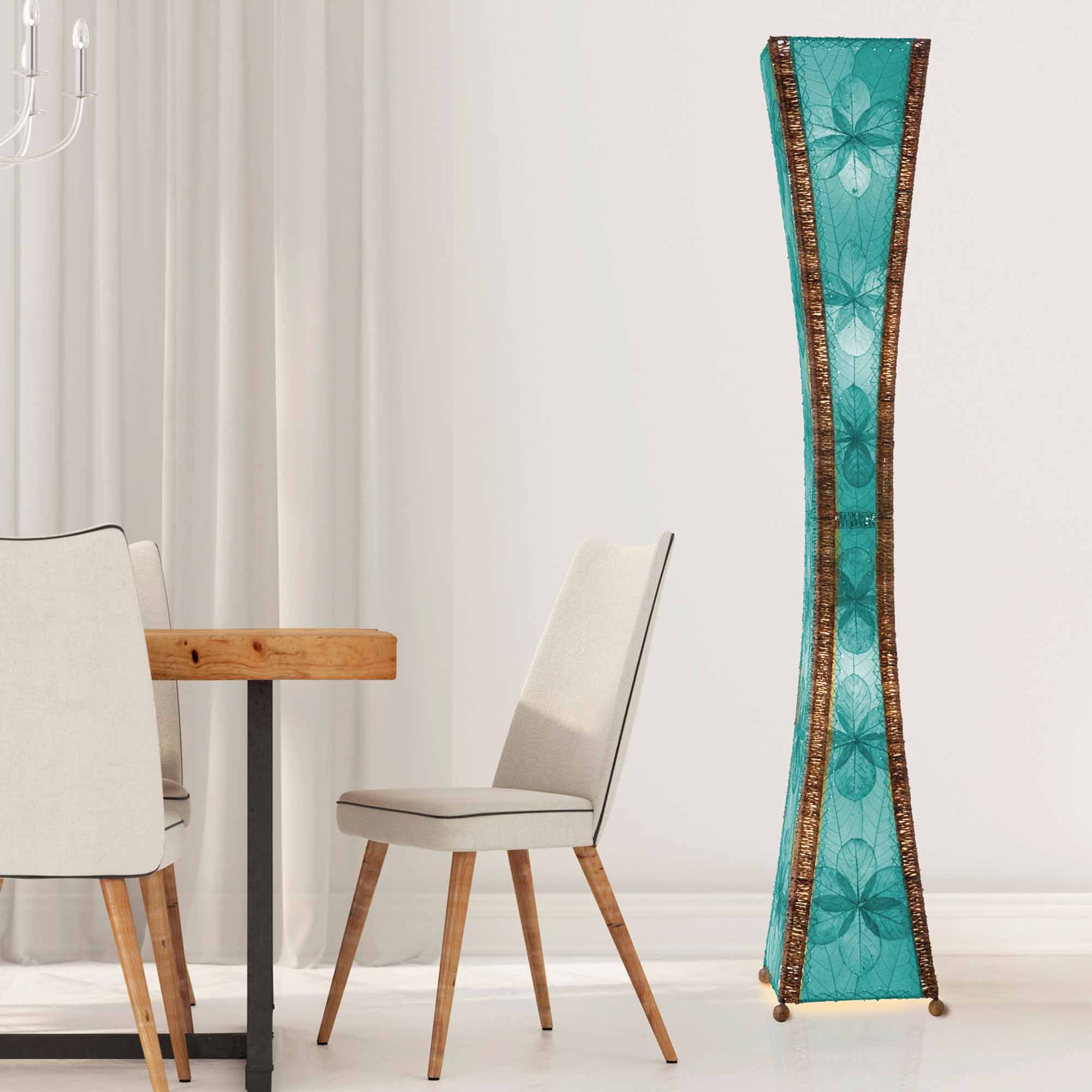 In a softly lit reading nook, crafted by the artisans of Eangee Home Design, the Hourglass Giant Floor Lamp in sea blue stands gracefully, featuring jackfruit leaf panels, abaca rope accents, wrought iron frame, eco friendly, handcrafted, adding warmth and character to the space.