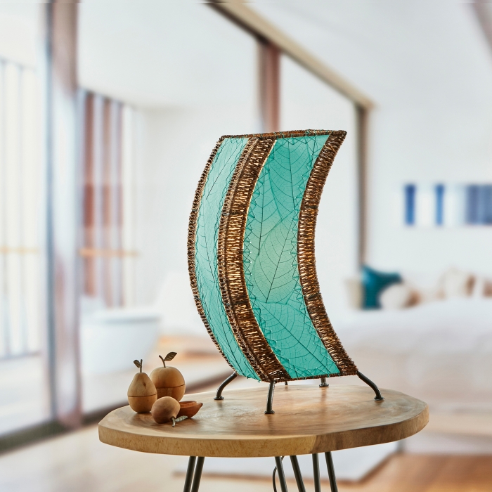 In a sun drenched entryway, crafted by the artisans of Eangee Home Design, the C Shape Table Lamp in sea blue stands gracefully, featuring fossilized cocoa leaf shade, abaca rope accents, fair trade, handcrafted, adding warmth and character to the space.