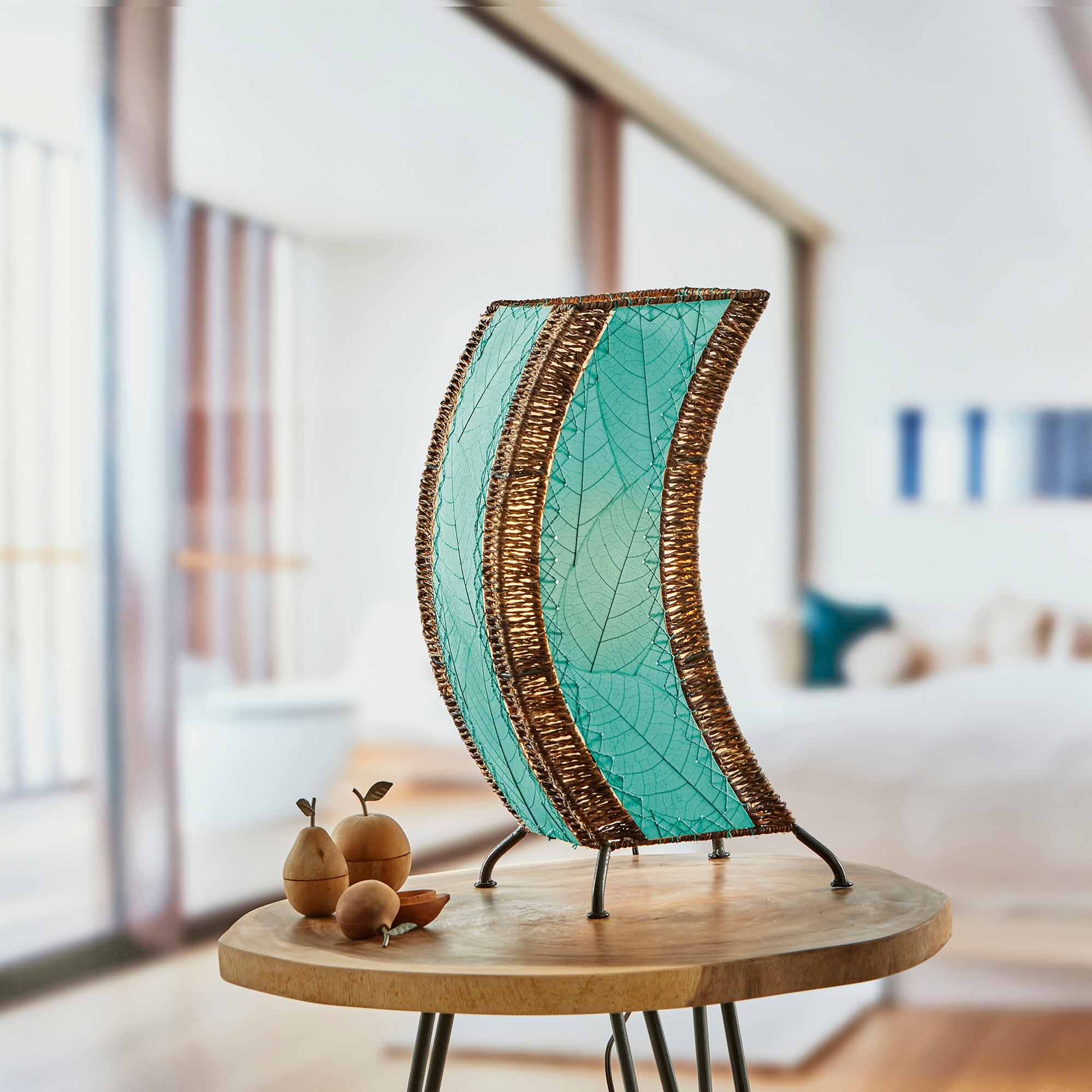In a sun drenched entryway, crafted by the artisans of Eangee Home Design, the C Shape Table Lamp in sea blue stands gracefully, featuring fossilized cocoa leaf shade, abaca rope accents, fair trade, handcrafted, adding warmth and character to the space.