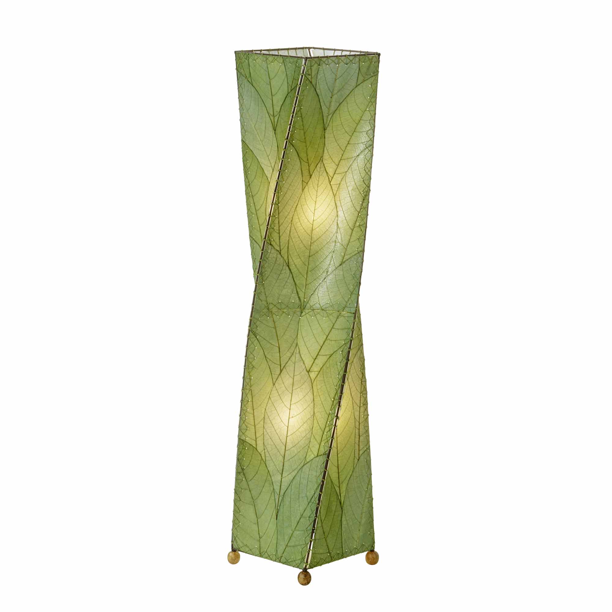 In a coastal inspired living room, crafted by the artisans of Eangee Home Design, the Twist Large Floor Lamp in green stands gracefully, featuring fossilized cocoa leaf shade, wrought iron frame, sustainably sourced, handcrafted, adding warmth and character to the space.