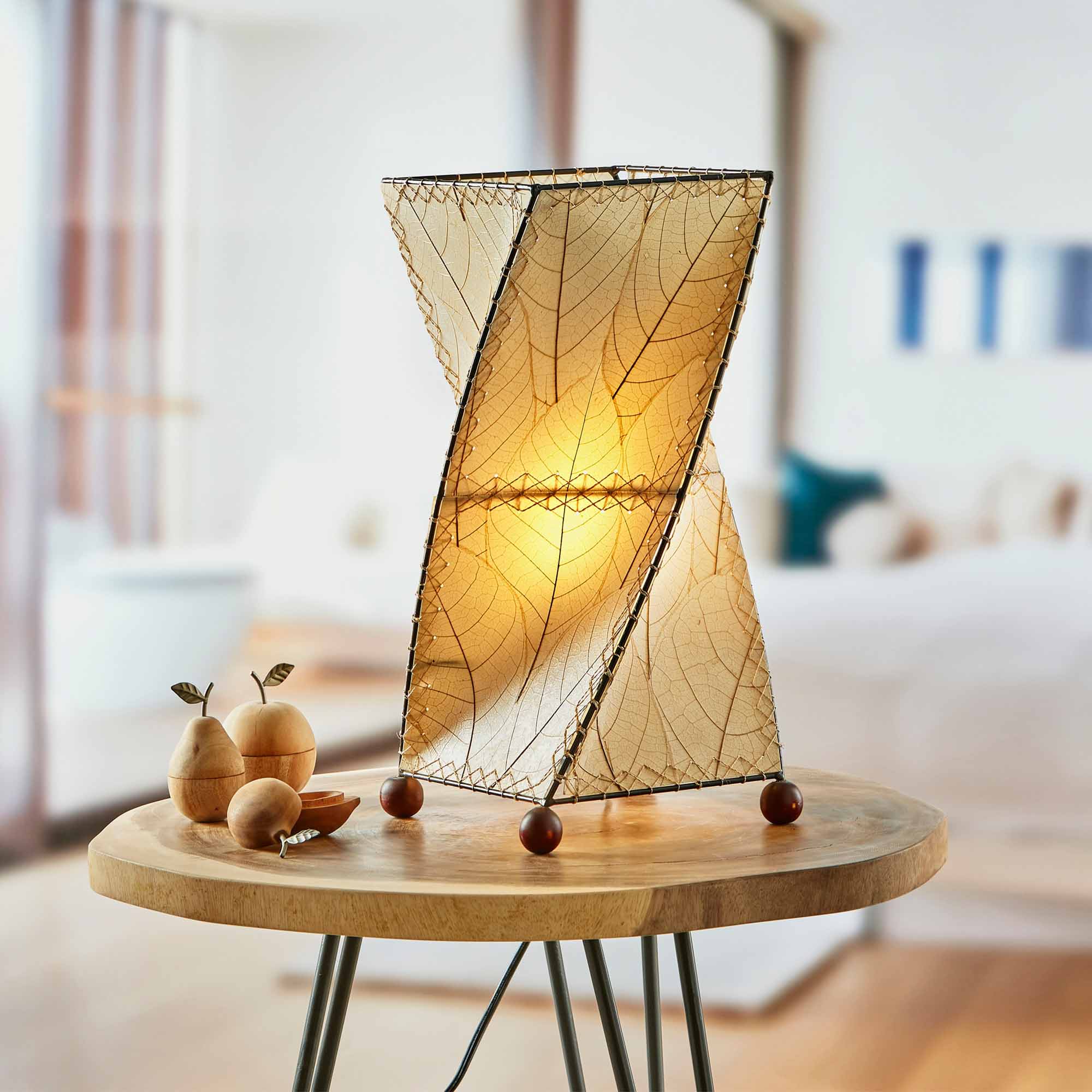 In a sun drenched entryway, crafted by the artisans of Eangee Home Design, the Twist Table Lamp in natural stands gracefully, featuring fossilized cocoa leaf shade, wrought iron frame, handcrafted, adding warmth and character to the space.