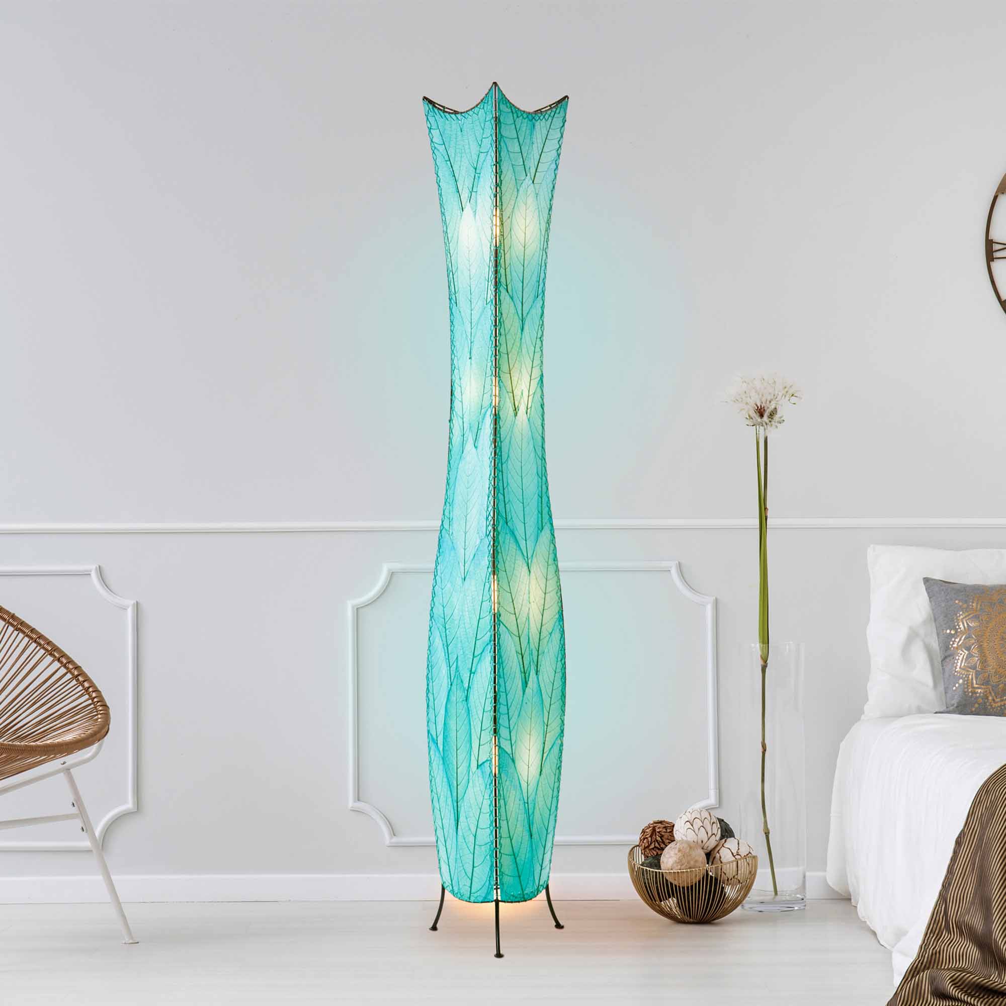 In a softly lit reading nook, crafted by the artisans of Eangee Home Design, the Flowerbud Giant Floor Lamp in sea blue stands gracefully, featuring fossilized cocoa leaf shade, adding warmth and character to the space.
