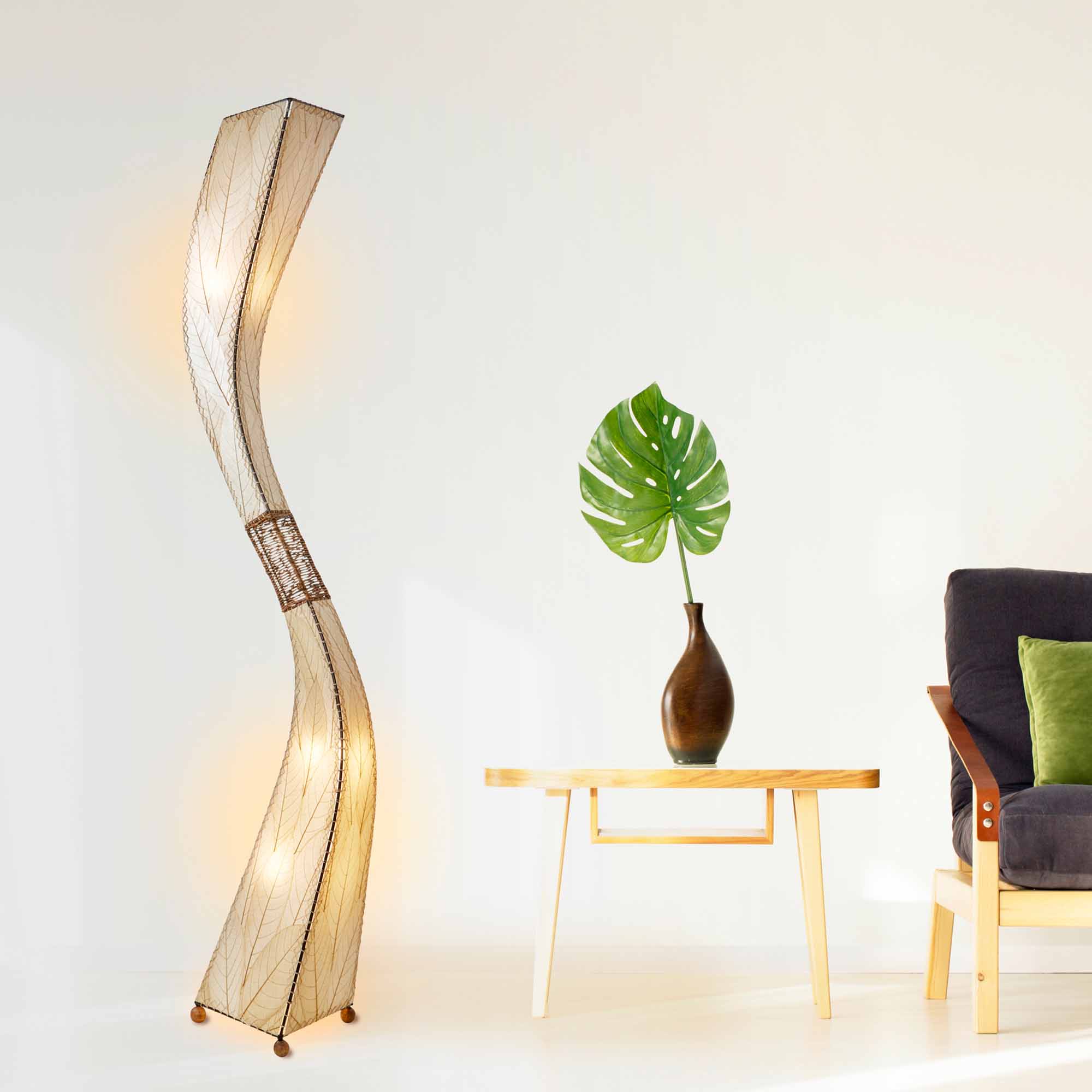 In a modern interior with earth tones, crafted by the artisans of Eangee Home Design, the Flow Giant Floor Lamp in natural stands gracefully, featuring fossilized cocoa leaf shade, abaca rope accents, eco friendly, adding warmth and character to the space.