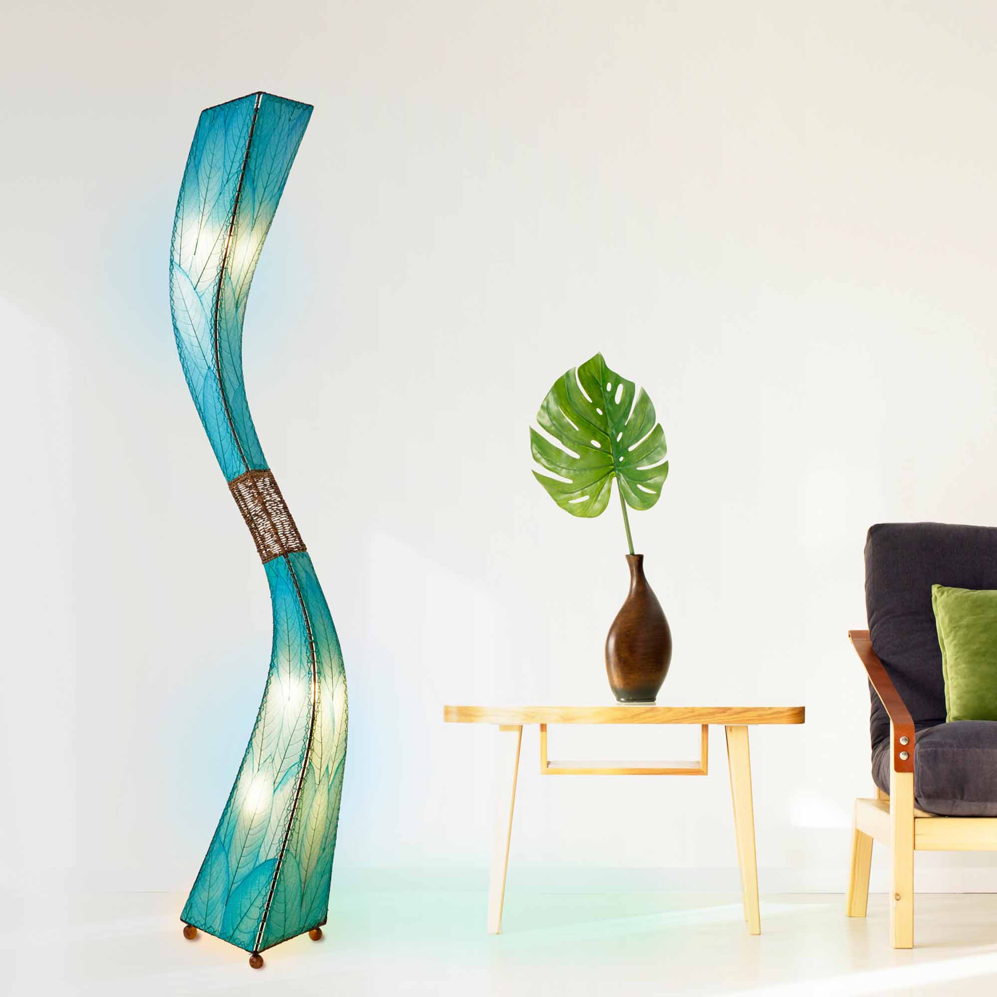 In a minimalist loft with natural textures, crafted by the artisans of Eangee Home Design, the Flow Giant Floor Lamp in sea blue stands gracefully, featuring fossilized cocoa leaf shade, abaca rope accents, eco friendly, adding warmth and character to the space.