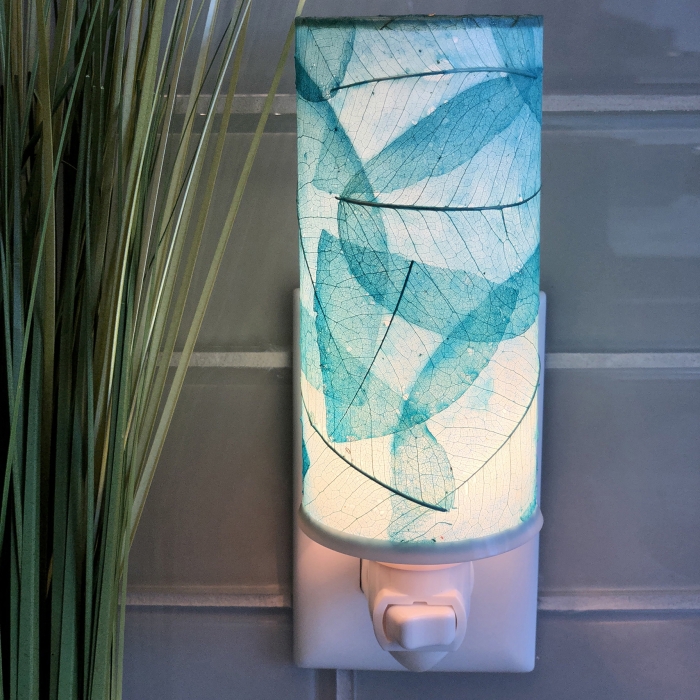 In a minimalist loft with natural textures, crafted by the artisans of Eangee Home Design, the Cylinder Nightlight in sea blue stands gracefully, featuring handcrafted detailing, fair trade, eco friendly, adding warmth and character to the space.