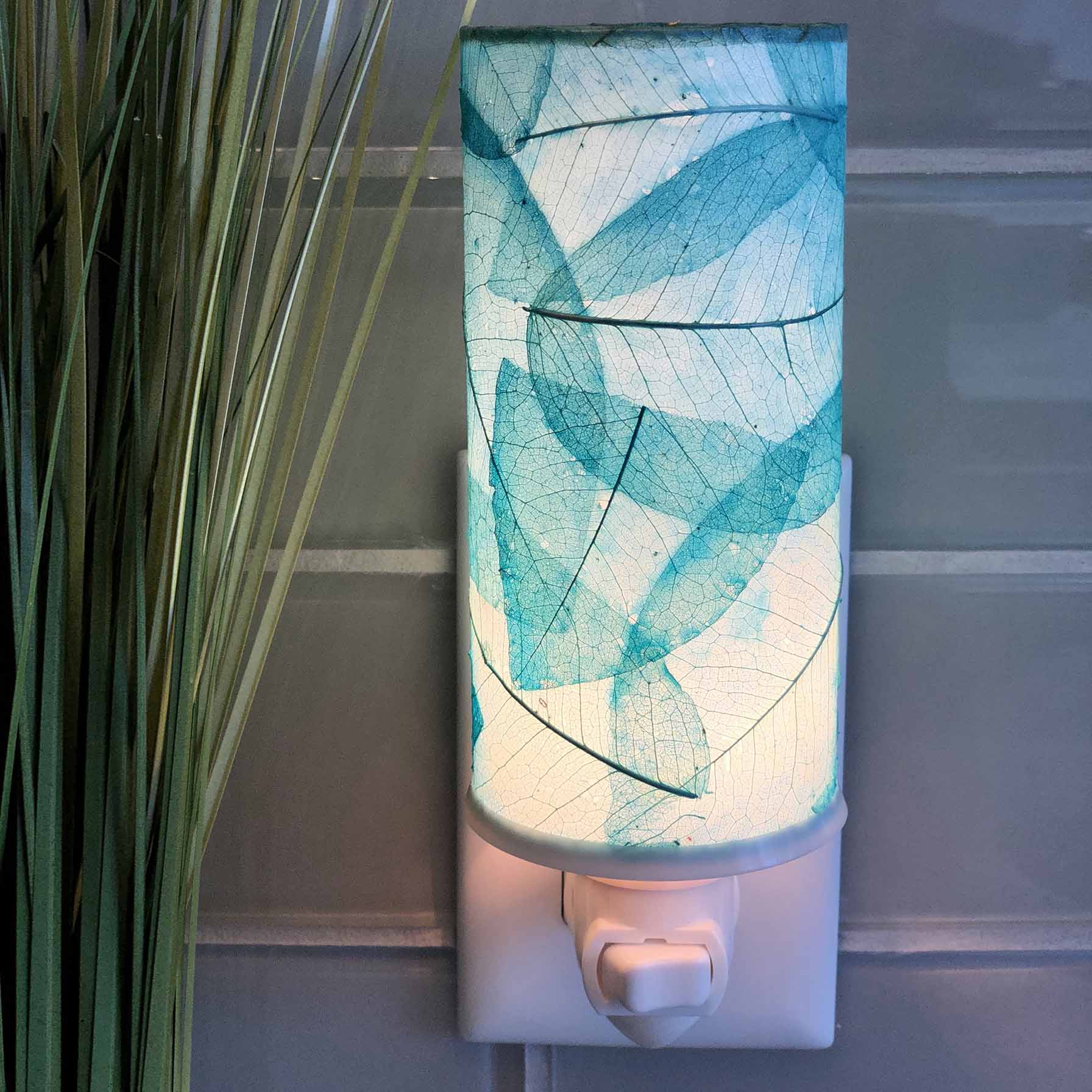In a minimalist loft with natural textures, crafted by the artisans of Eangee Home Design, the Cylinder Nightlight in sea blue stands gracefully, featuring handcrafted detailing, fair trade, eco friendly, adding warmth and character to the space.