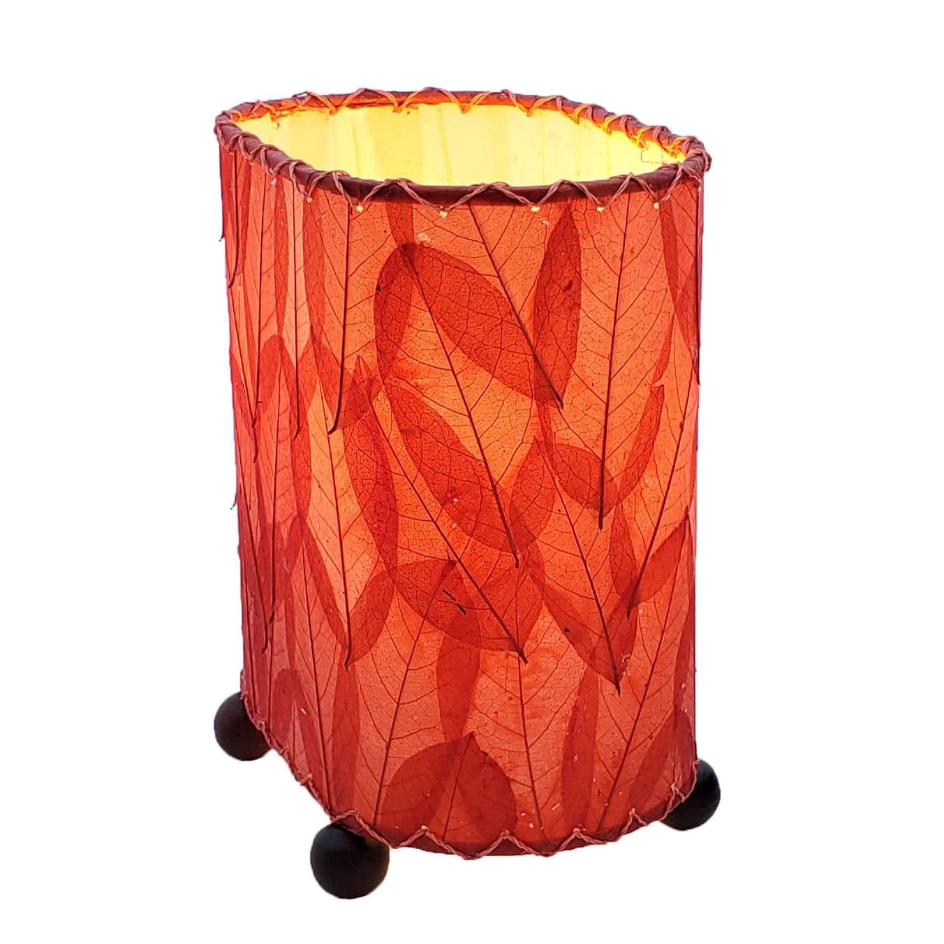 Crafted by the artisans of Eangee Home Design, the Mini Guyabano Table Lamp in red against a clean backdrop, featuring fossilized cocoa leaf shade, guyabano leaf shade, wrought iron frame.