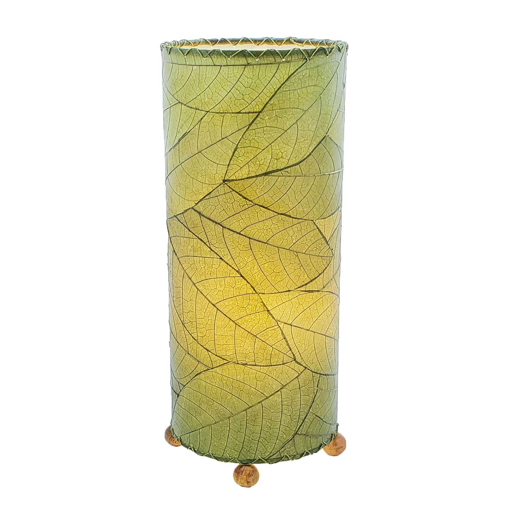 Crafted by the artisans of Eangee Home Design, the Cocoa Leaf Cylinder Table Lamp in green against a clean backdrop, featuring fossilized cocoa leaf shade, wrought iron frame, handcrafted.