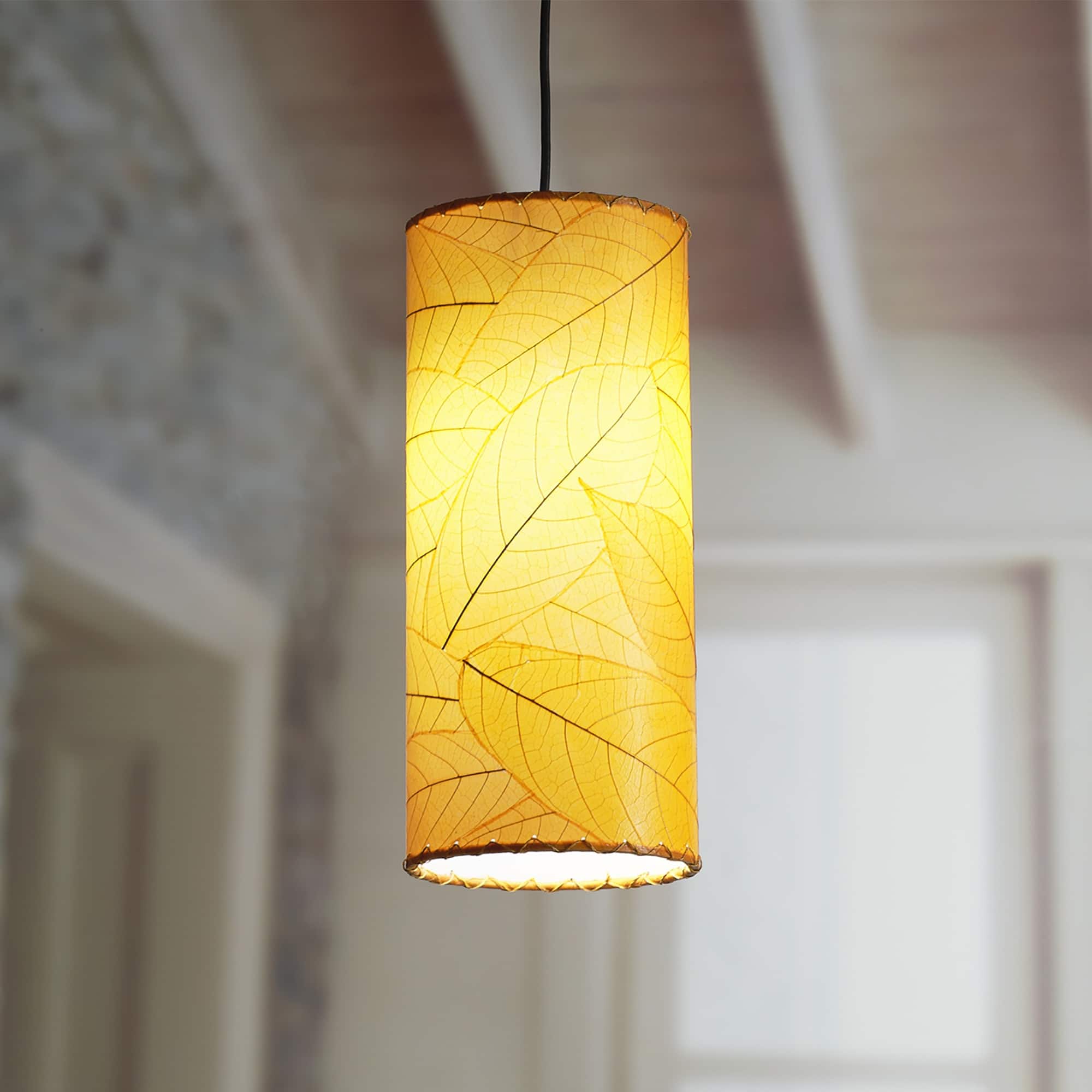 Crafted by the artisans of Eangee Home Design, the Cylinder Pendant in orange against a clean backdrop, featuring fossilized cocoa leaf shade, handcrafted.