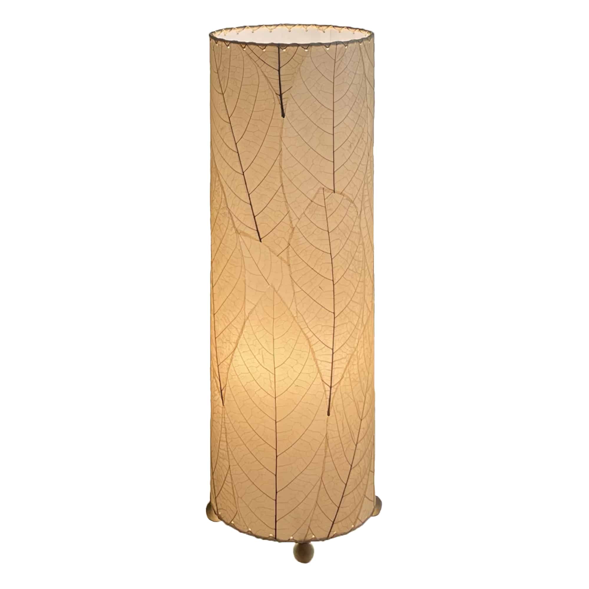 Crafted by the artisans of Eangee Home Design, the 24 Inch Cocoa Leaf Cylinder Table Lamp in natural against a clean backdrop, featuring fossilized cocoa leaf shade, fair trade, eco friendly, sustainably sourced, handcrafted.