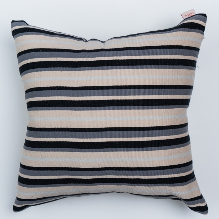 Black outdoor pillow crafted by the artisans of Magnolia Casual called the Rayitas Pillow Gray Black featuring traditional backstrap loom weave, handwoven textile, handcrafted shown against a clean backdrop featuring shades of gray and black.