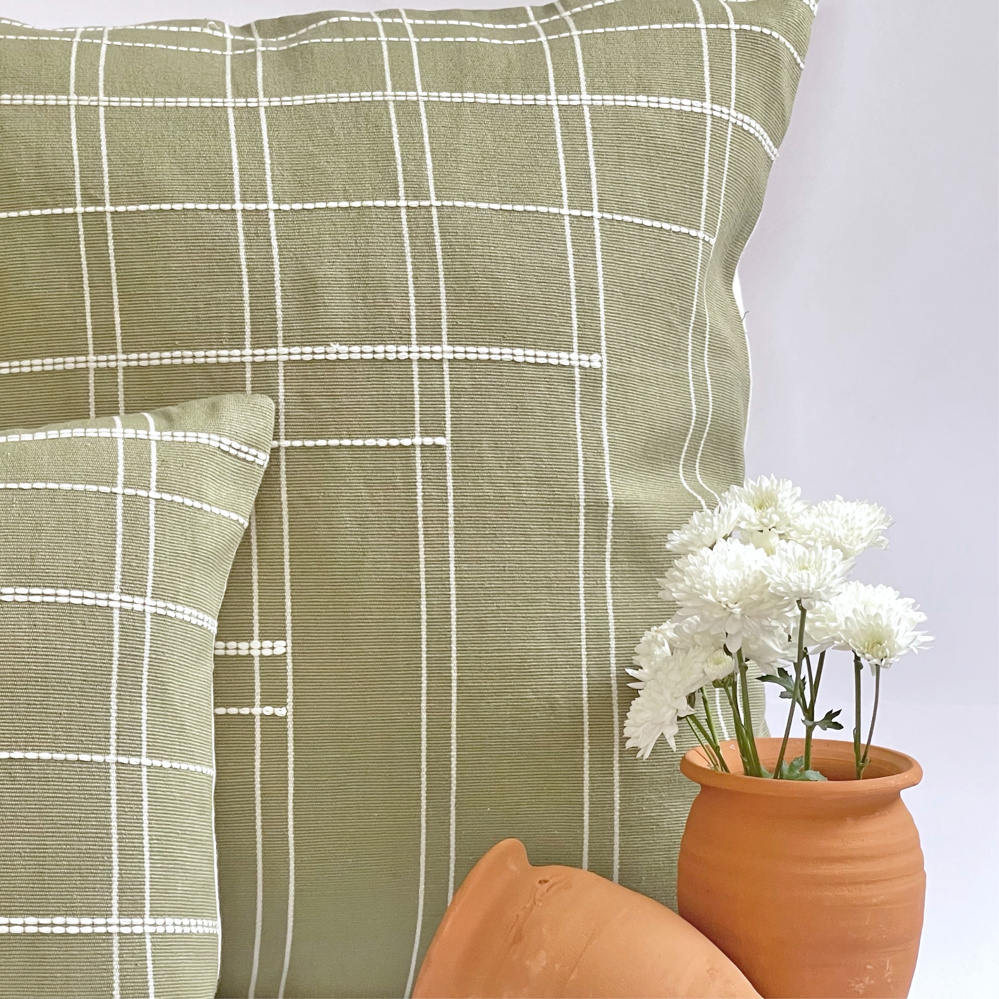 Green pillow cover crafted by the artisans of Dos Tierras called the Broken Grid Pillow Cover Green featuring handwoven textile, handcrafted shown against a clean backdrop featuring with a grid motif and shades of green.