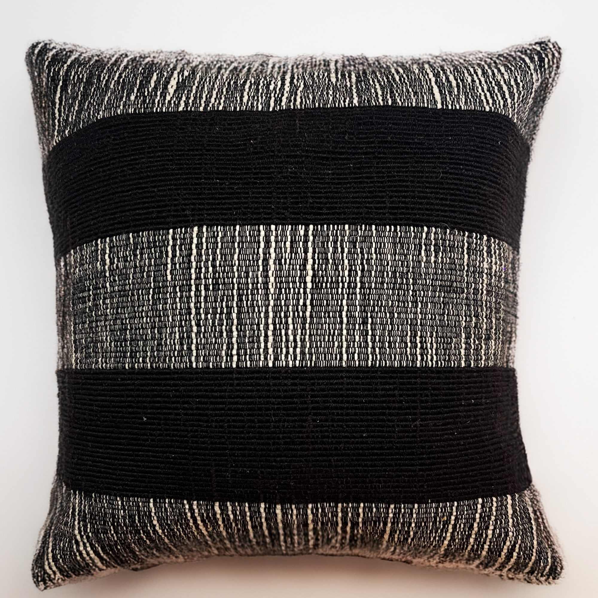 Black pillow cover crafted by the artisans of Dos Tierras called the Wool Pillow Cover Black featuring handwoven textile, handcrafted shown against a clean backdrop featuring shades of black.