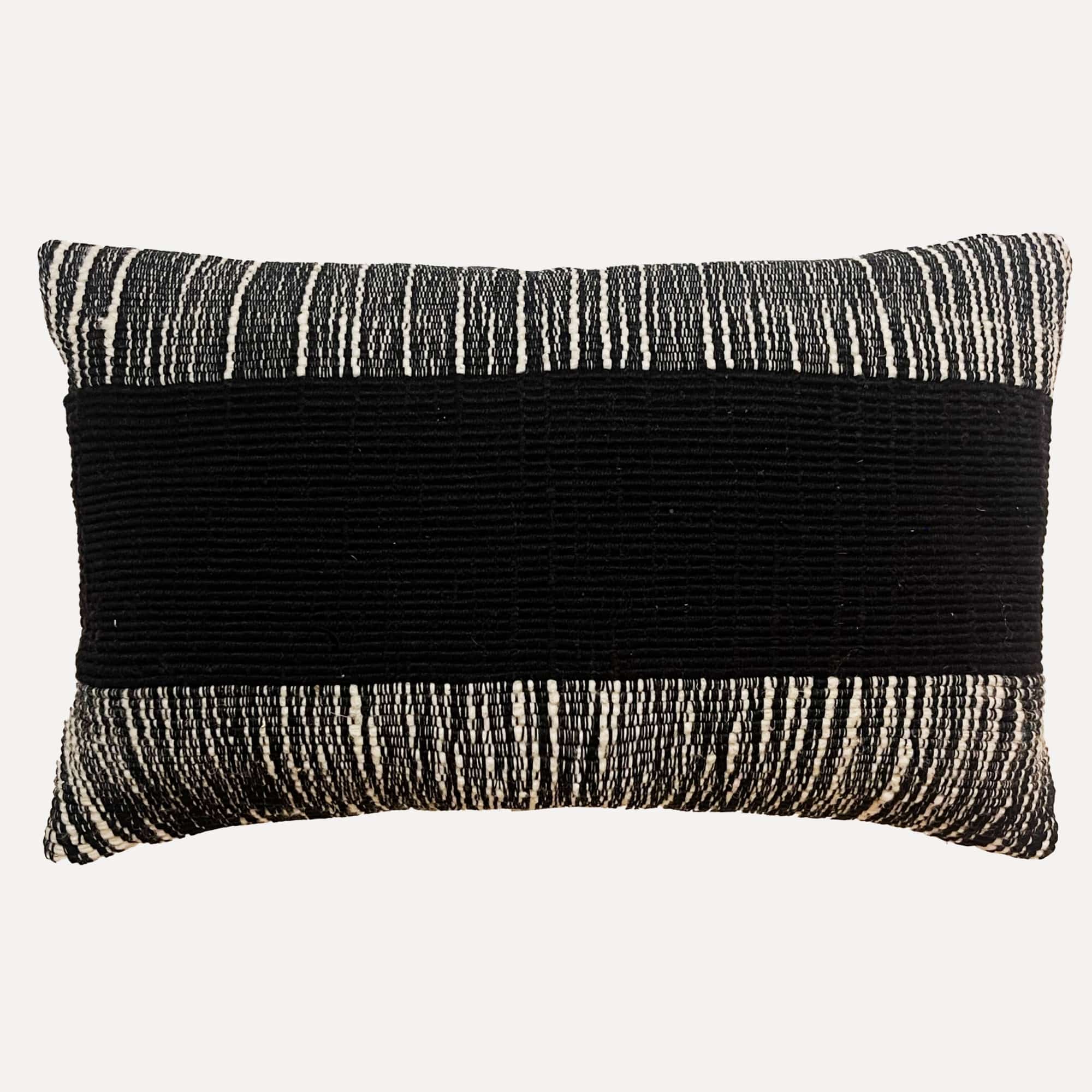 Black pillow cover crafted by the artisans of Dos Tierras called the Wool Lumbar Pillow Cover Black featuring handwoven textile, handcrafted shown against a clean backdrop featuring shades of black.