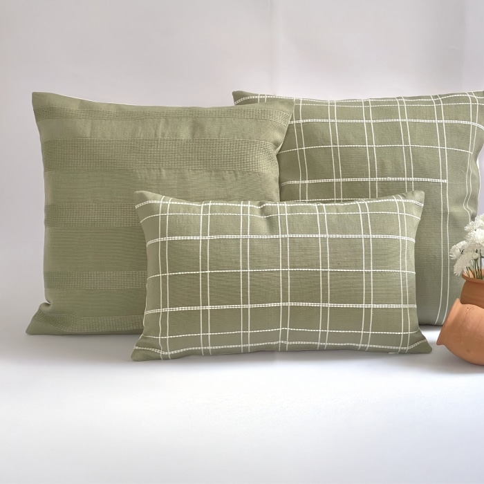 Green pillow cover crafted by the artisans of Dos Tierras called the Broken Grid Pillow Cover Green featuring handwoven textile, handcrafted shown against a clean backdrop featuring with a grid motif and shades of green.