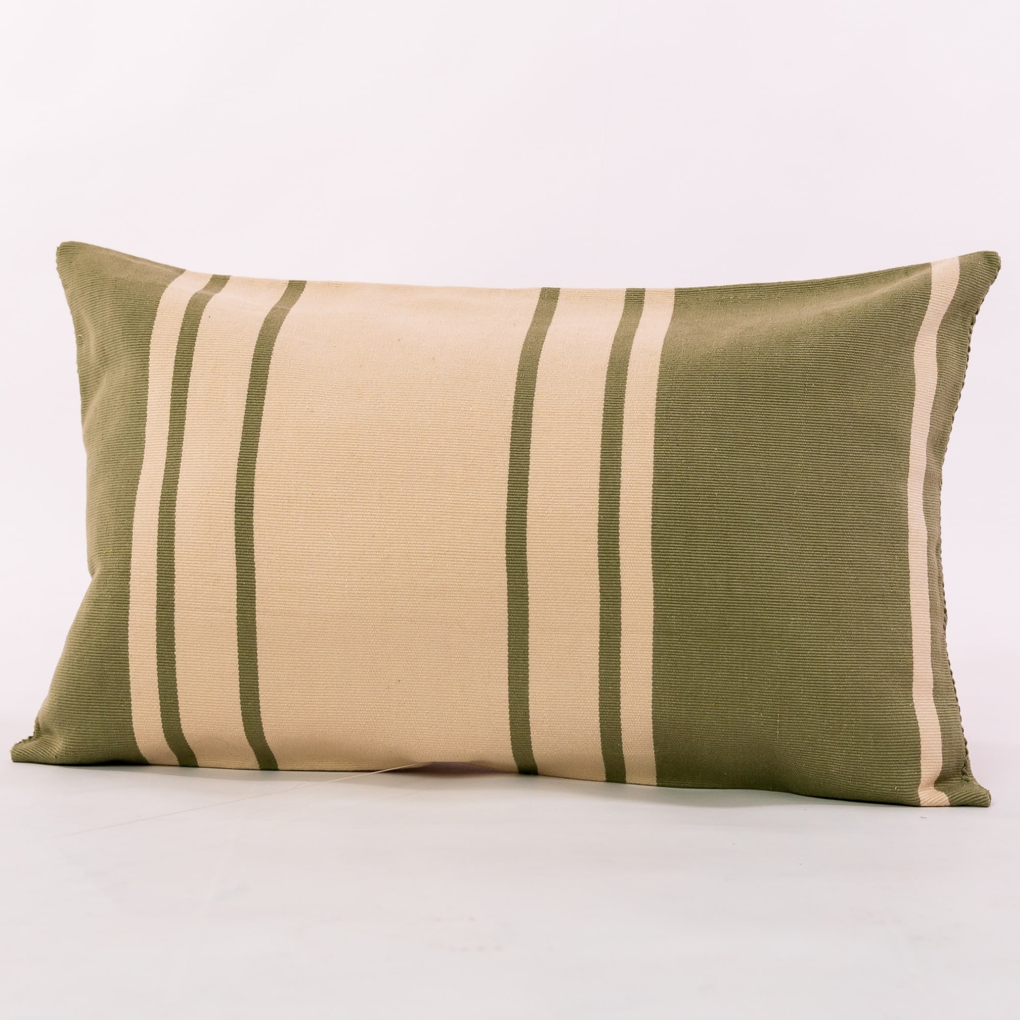 Green outdoor pillow crafted by the artisans of Dos Tierras called the Toloyal Lumbar Pillow Green featuring handwoven textile, handcrafted shown against a clean backdrop featuring shades of green.