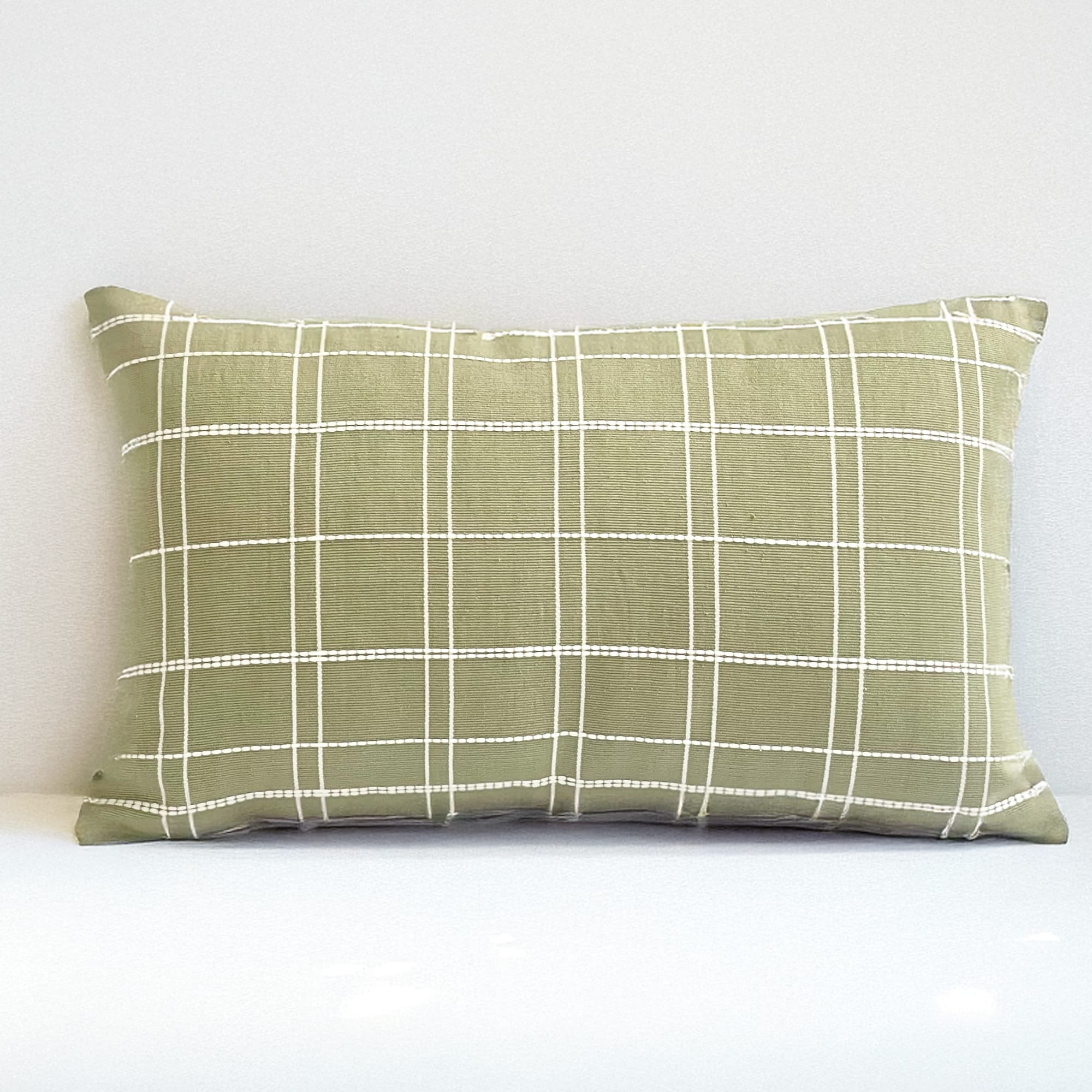 Green pillow cover crafted by the artisans of Dos Tierras called the Grid Lumbar Pillow Cover Green featuring handwoven textile, handcrafted shown against a clean backdrop featuring with a grid motif and shades of green.