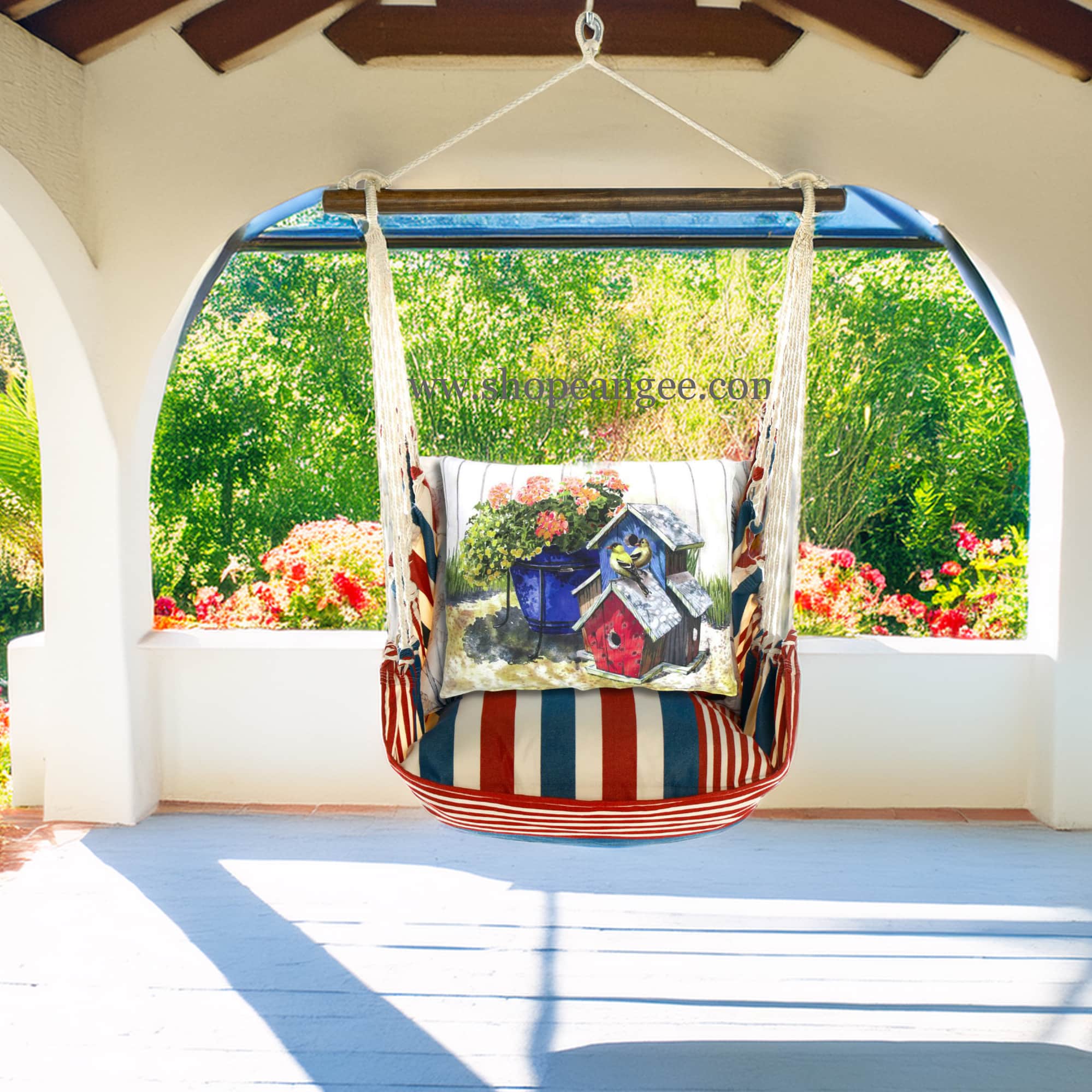 In a shaded porch swing a multi colored outdoor swing crafted by the artisans of Magnolia Casual called the Swing Set 4 piece Stars & Stripes w/ Birdhouses & Flowers is displayed featuring 100 percent weather resistant fabric, weather resistant polyester fabric, handcrafted adding comfort and style to the space featuring with a stripes motif.