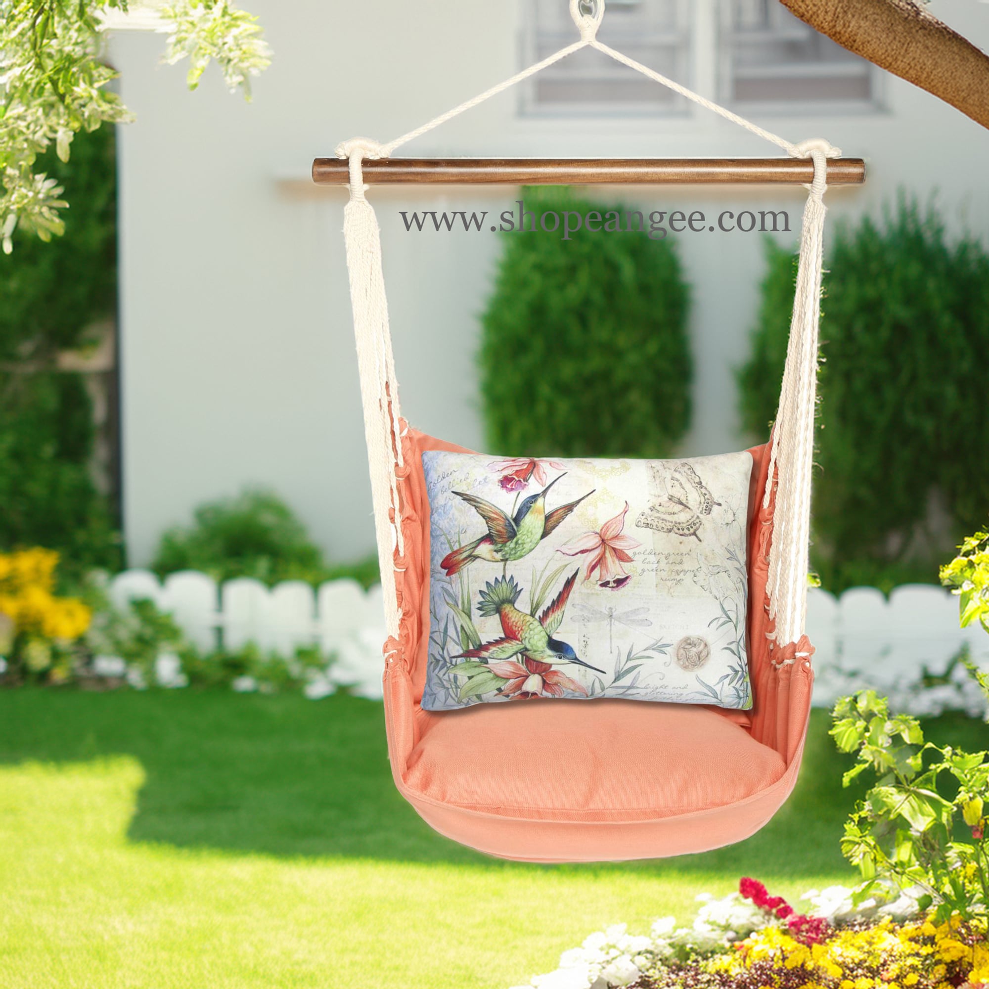 In a cozy garden seating area a multi colored outdoor swing crafted by the artisans of Magnolia Casual called the Swing Set 4 piece Living Coral w/ Hummingbirds is displayed featuring 100 percent weather resistant fabric, weather resistant polyester fabric, handcrafted adding comfort and style to the space featuring with a coral motif and shades of coral.