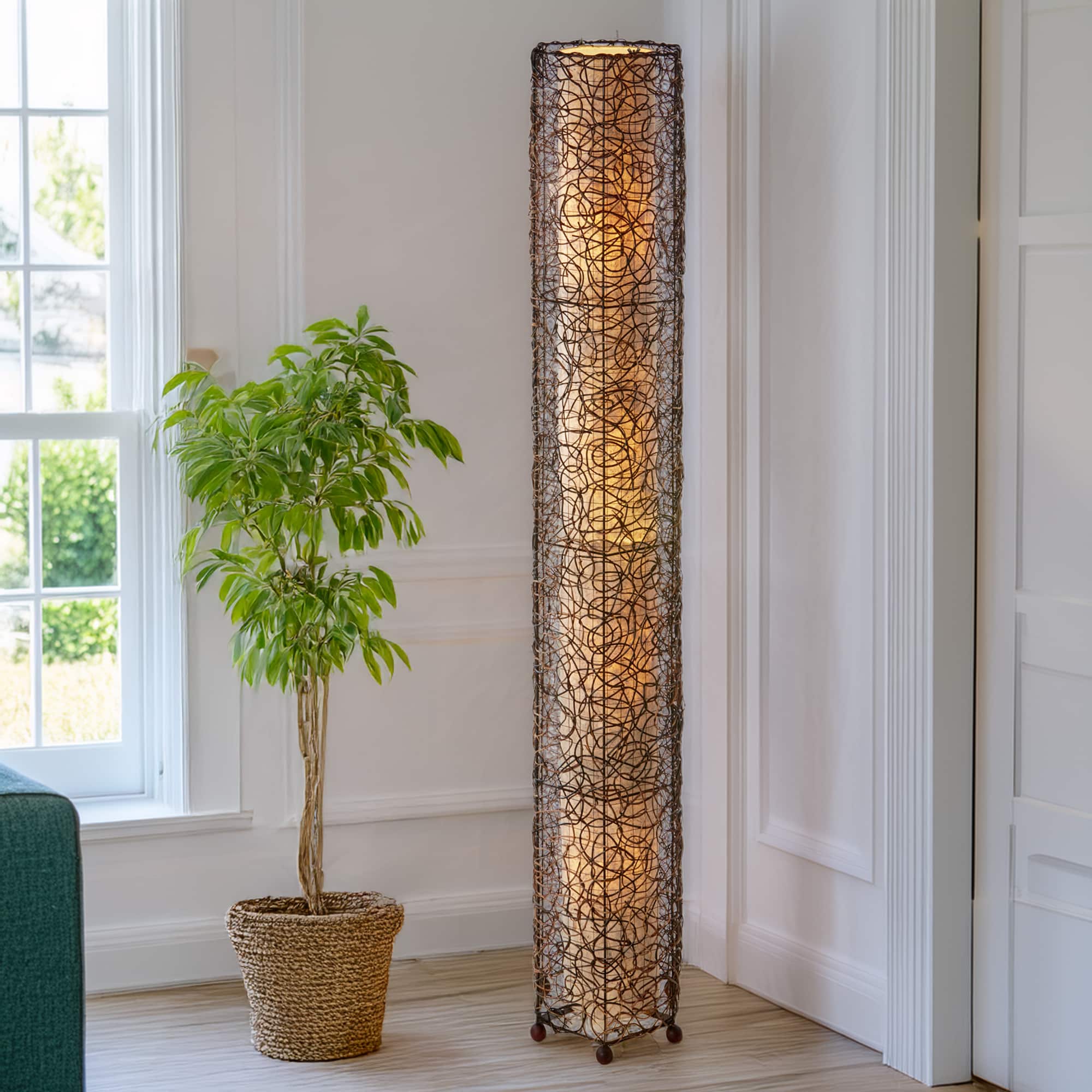 In a softly lit reading nook, crafted by the artisans of Eangee Home Design, the Nito Giant Floor Lamp in natural stands gracefully, featuring recycled paper shade, eco friendly, sustainably sourced, recycled materials, adding warmth and character to the space.