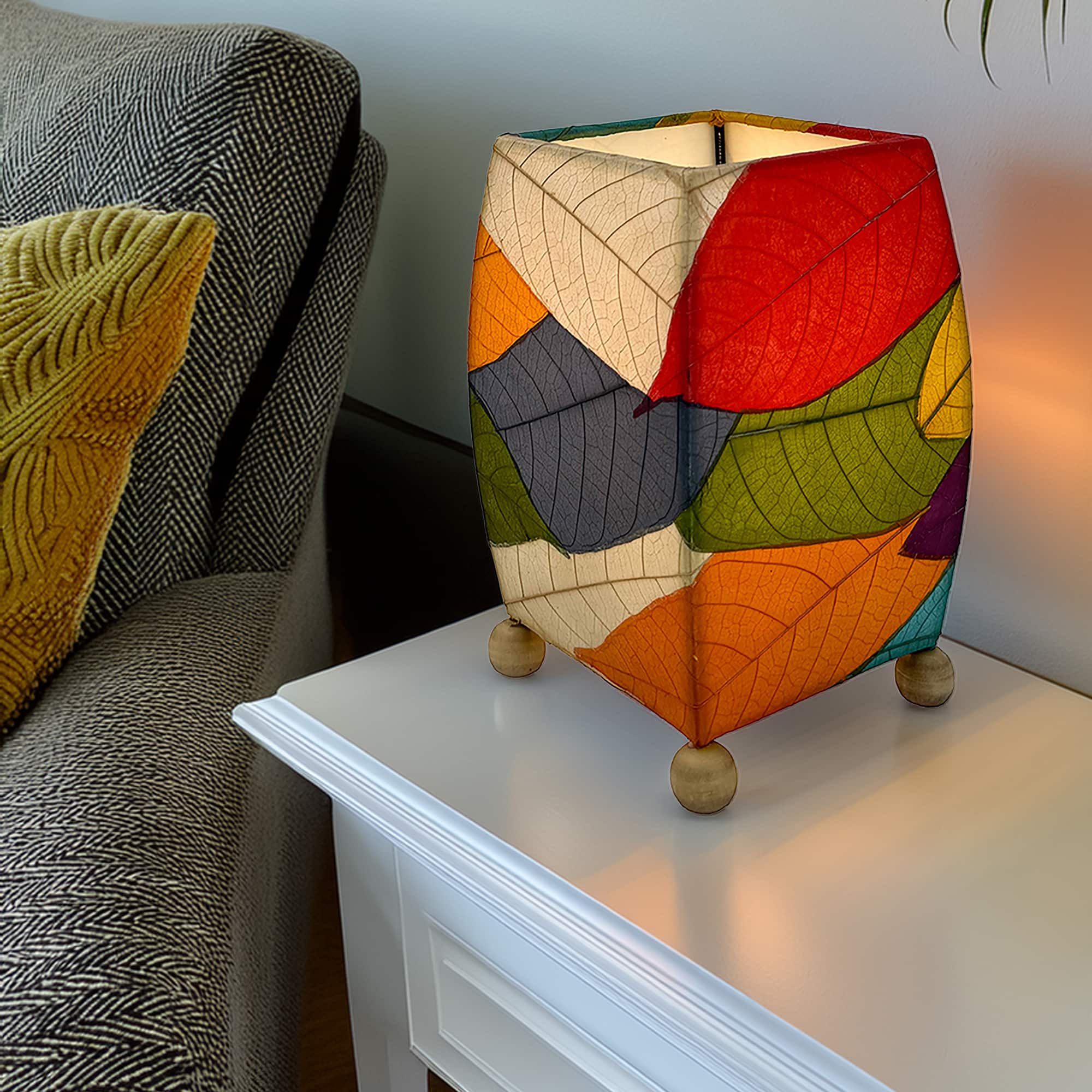 In a coastal inspired living room, crafted by the artisans of Eangee Home Design, the Mini Square Cocoa Leaf Table Lamp in multi color stands gracefully, featuring fossilized cocoa leaf shade, wrought iron frame, fair trade, eco friendly, sustainably sourced, handcrafted, adding warmth and character to the space.