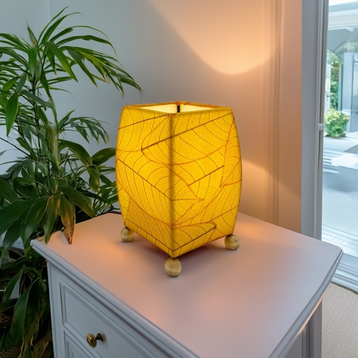 Crafted by the artisans of Eangee Home Design, the Mini Square Cocoa Leaf Table Lamp in yellow against a clean backdrop, featuring fossilized cocoa leaf shade, wrought iron frame, fair trade, eco friendly, sustainably sourced, handcrafted.