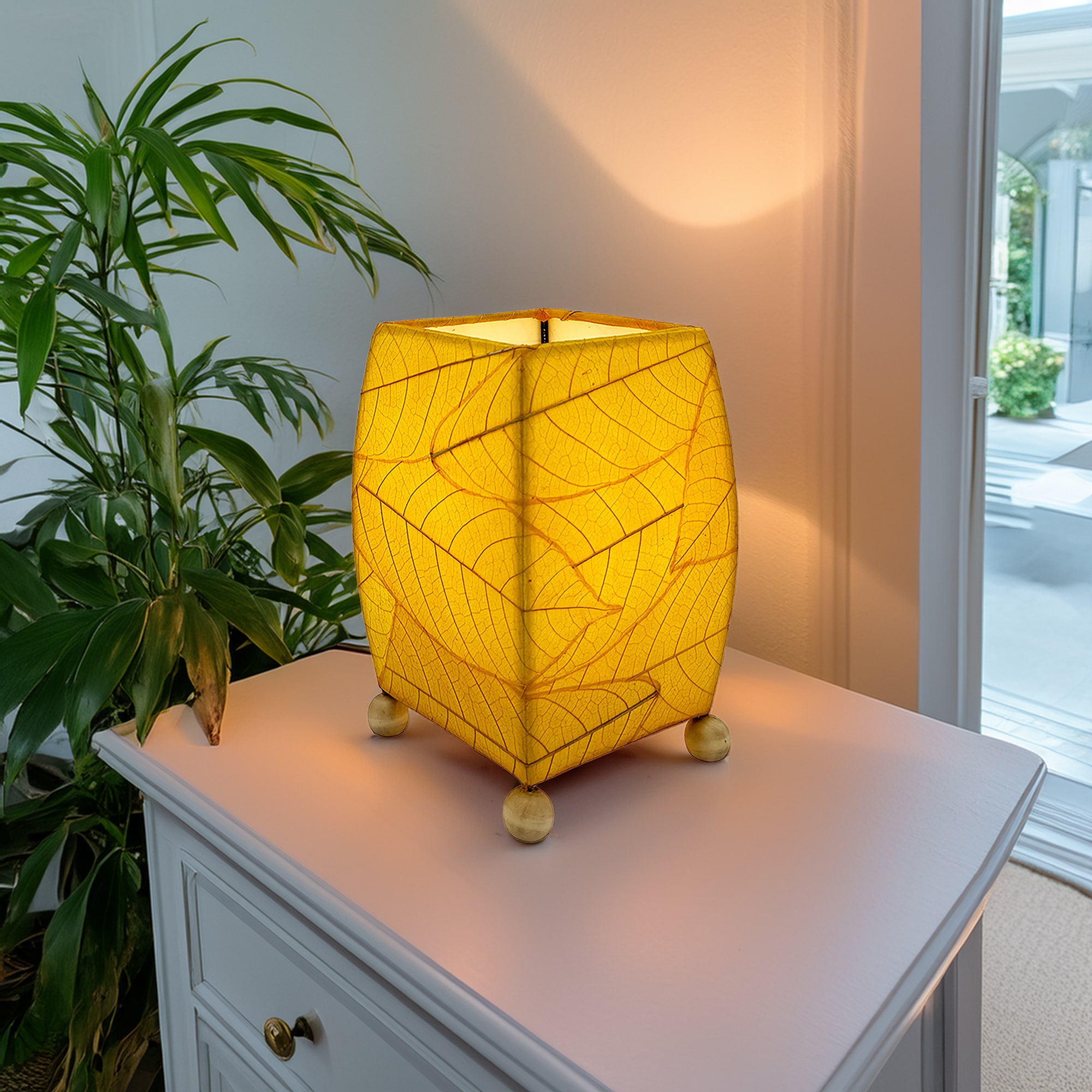 Crafted by the artisans of Eangee Home Design, the Mini Square Cocoa Leaf Table Lamp in yellow against a clean backdrop, featuring fossilized cocoa leaf shade, wrought iron frame, fair trade, eco friendly, sustainably sourced, handcrafted.