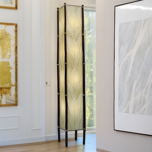 In a minimalist loft with natural textures, crafted by the artisans of Eangee Home Design, the Fortune Giant Floor Lamp in natural stands gracefully, featuring fossilized cocoa leaf shade, abaca rope accents, rattan leg supports, wrought iron frame, eco friendly, adding warmth and character to the space.