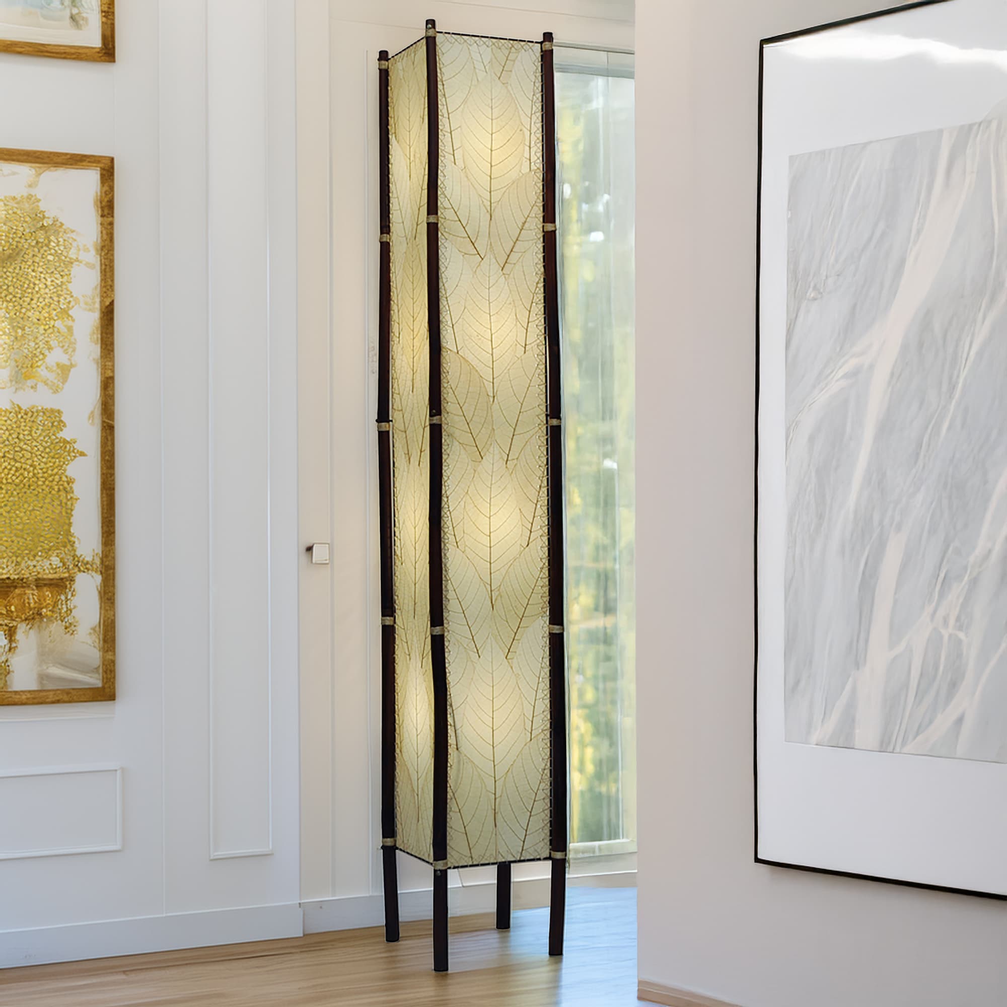 In a minimalist loft with natural textures, crafted by the artisans of Eangee Home Design, the Fortune Giant Floor Lamp in natural stands gracefully, featuring fossilized cocoa leaf shade, abaca rope accents, rattan leg supports, wrought iron frame, eco friendly, adding warmth and character to the space.