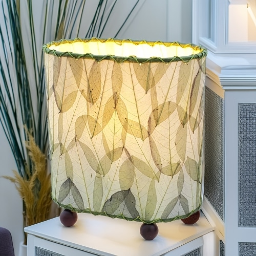Crafted by the artisans of Eangee Home Design, the Mini Guyabano Table Lamp in green against a clean backdrop, featuring fossilized cocoa leaf shade, guyabano leaf shade, wrought iron frame.